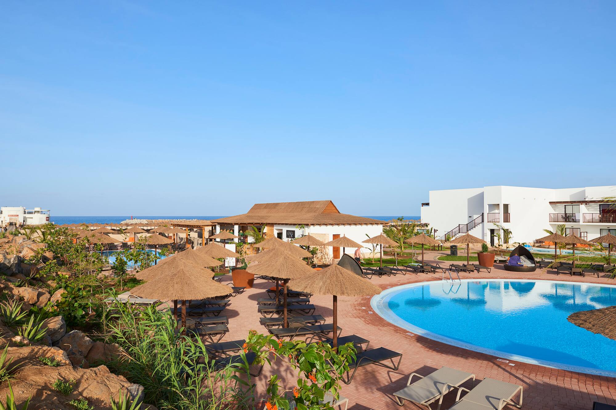 a pool with umbrellas and chairs and a building with a body of water