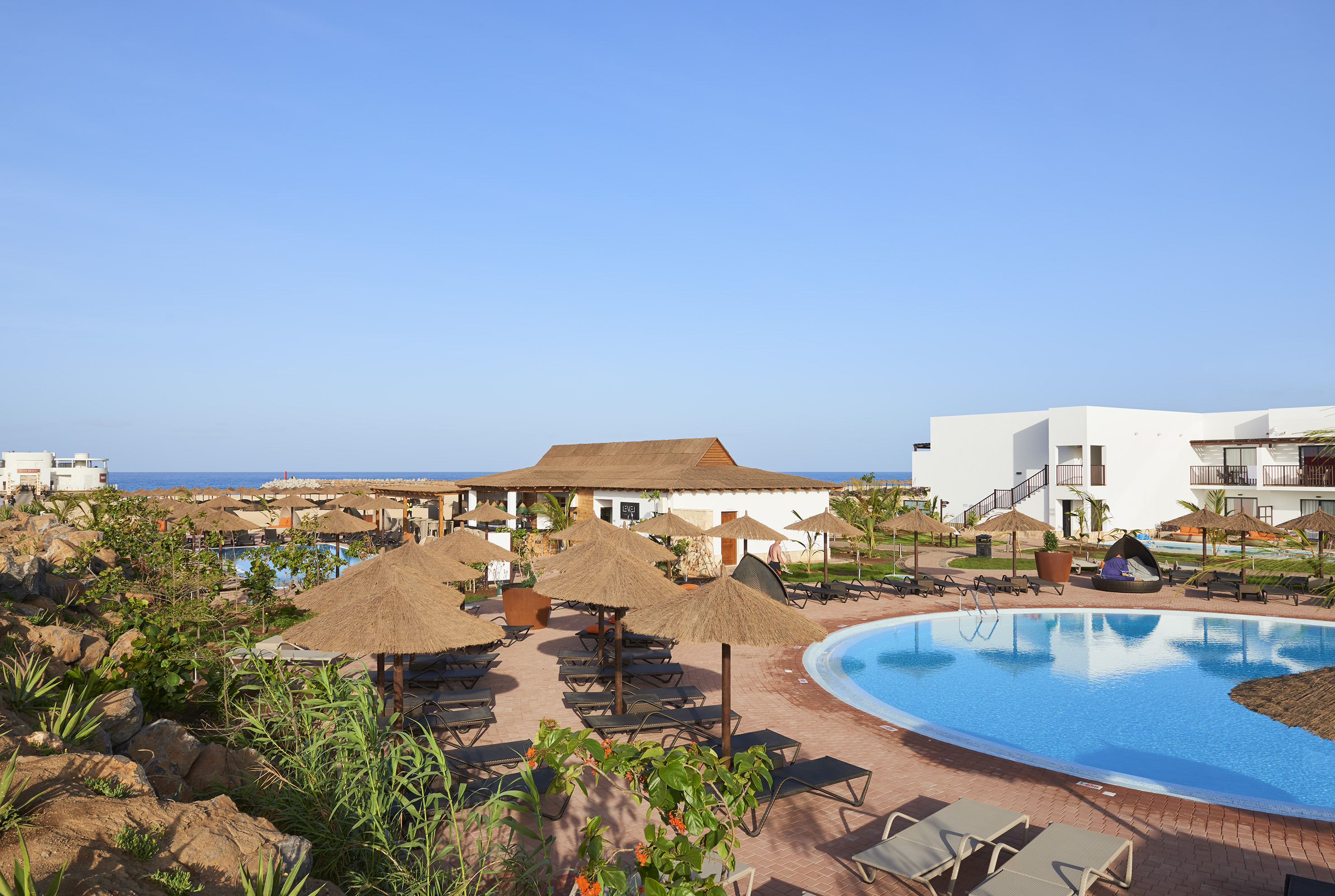 a pool with umbrellas and chairs and a building with a body of water