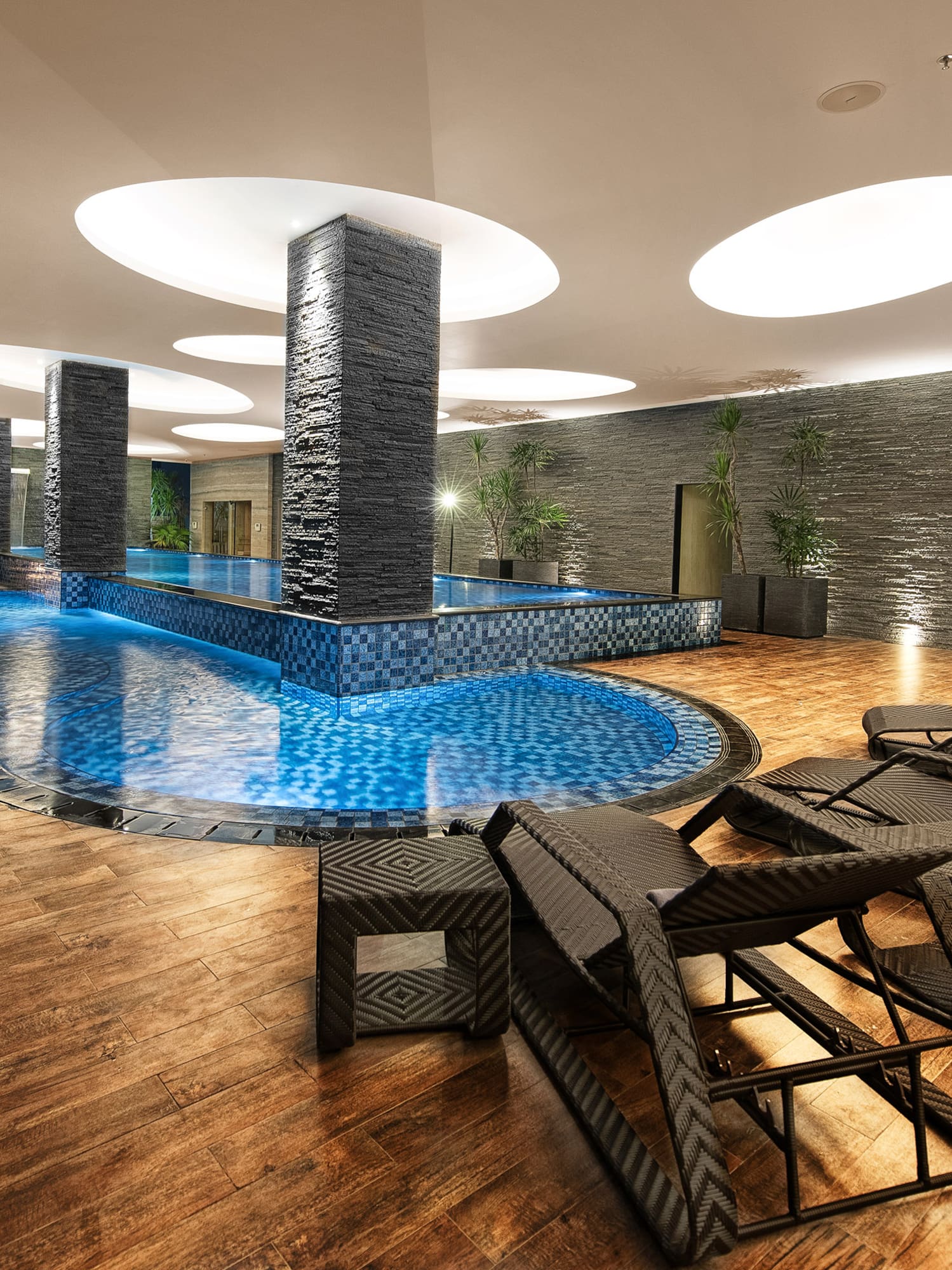 a pool with chairs and a large stone wall