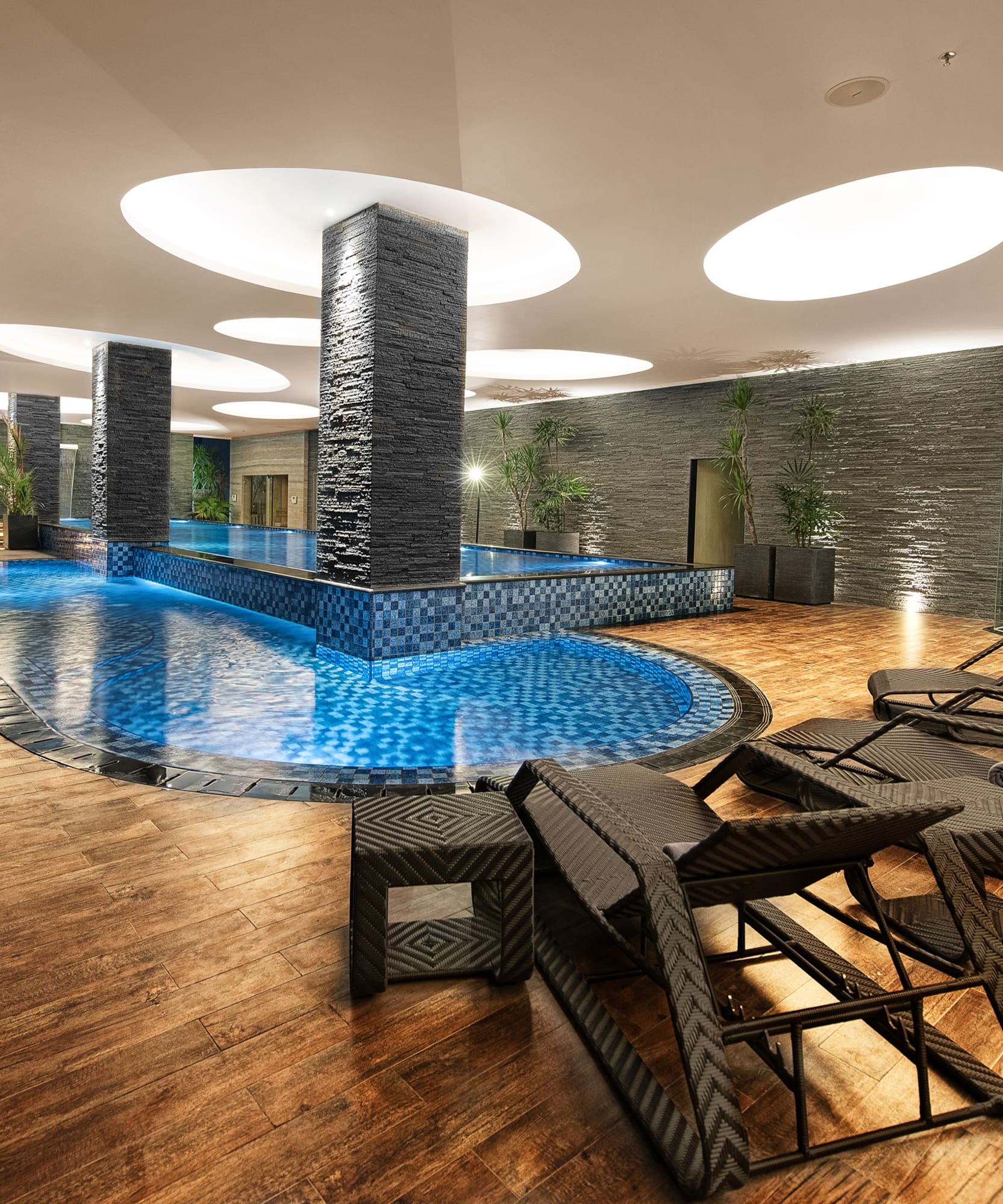 a pool with chairs and a large stone wall