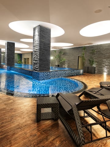 a pool with chairs and a large stone wall