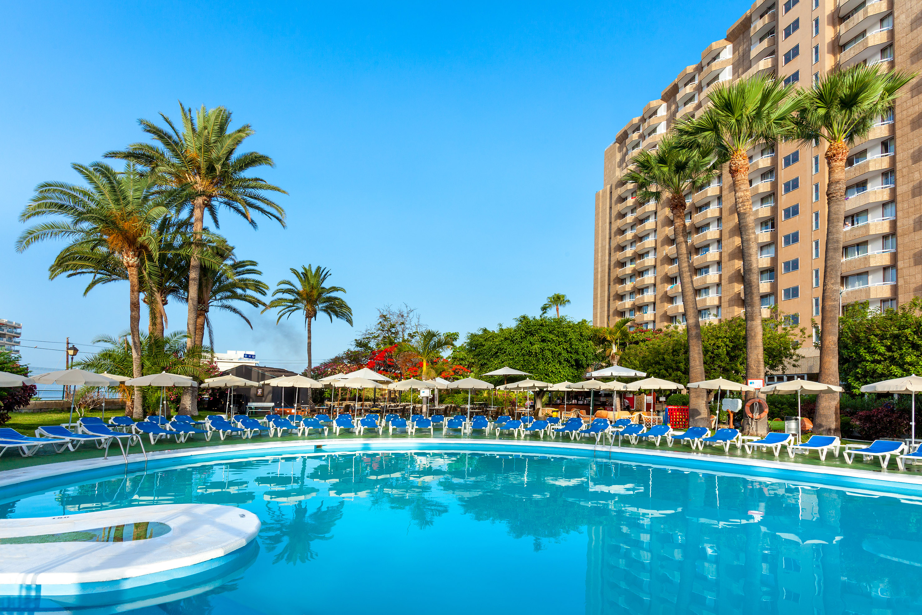 a pool with umbrellas and chairs in front of a building