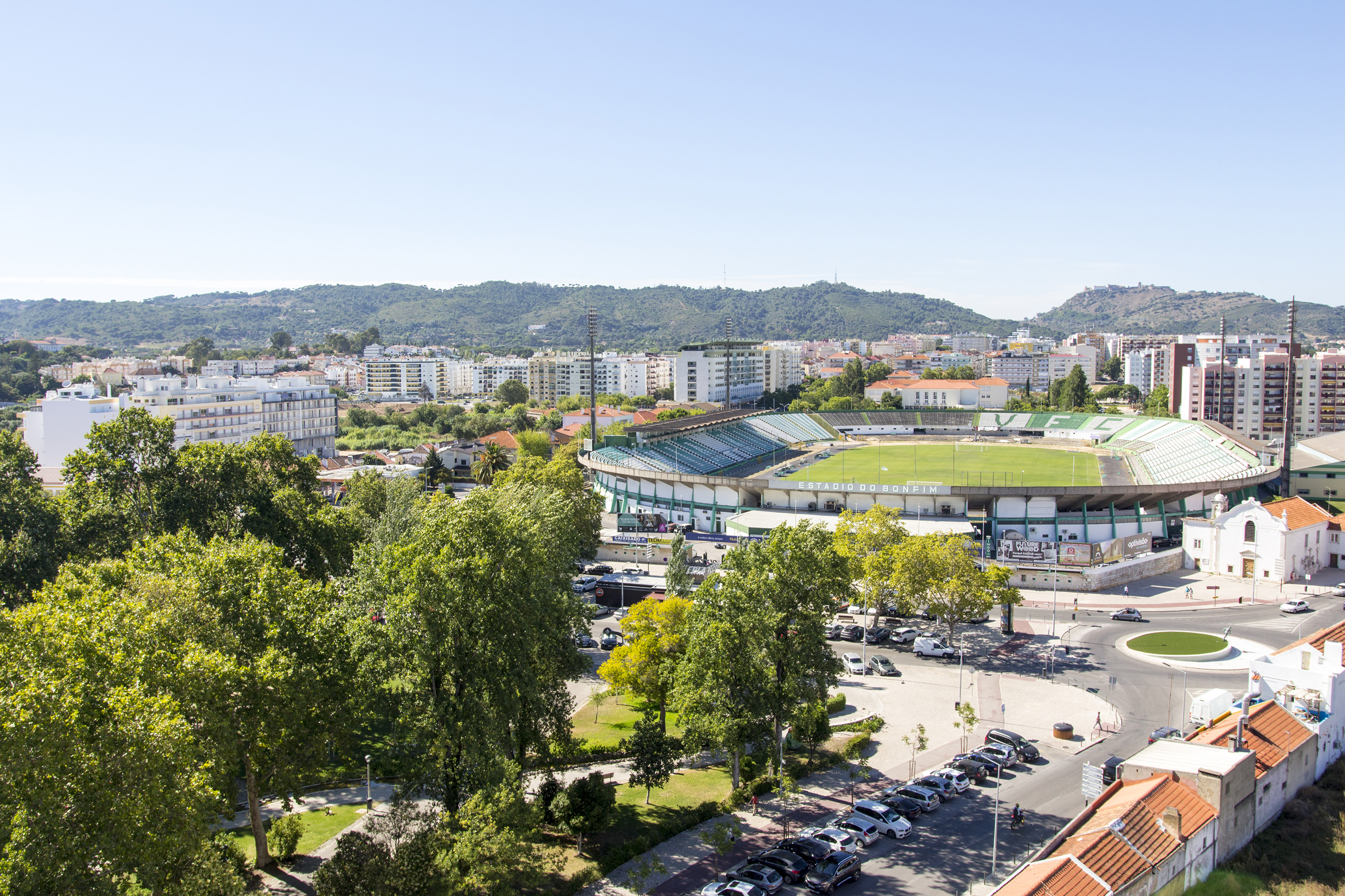 Estádio do Bonfim stadium in Setúbal, Portugal, with city buildings and mountains.