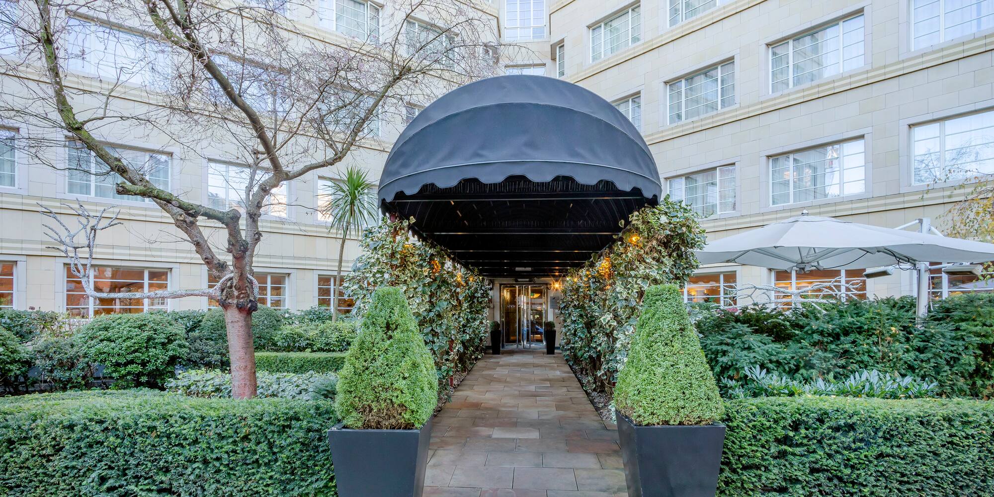 a black canopy with a black cover and bushes in front of a building