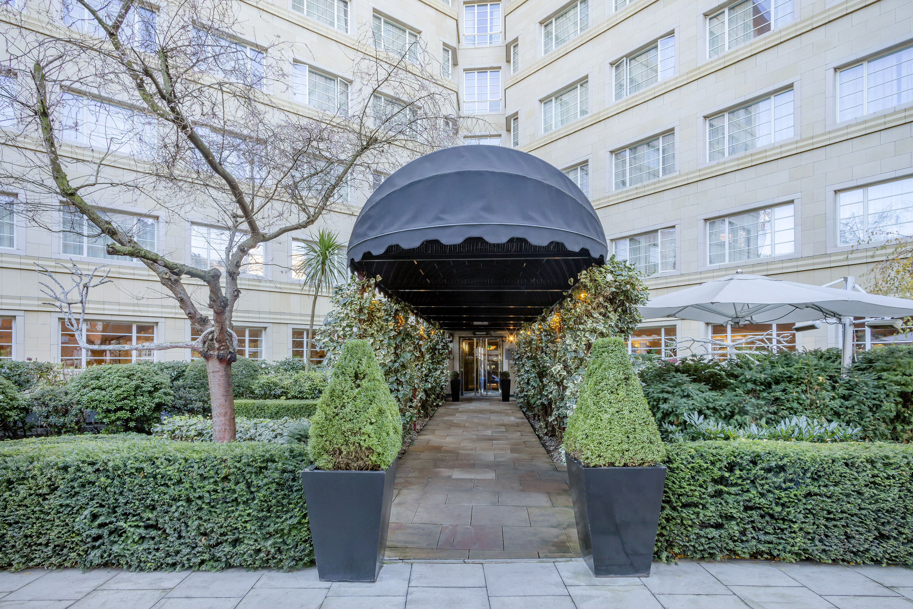 a black canopy with a black cover and bushes in front of a building