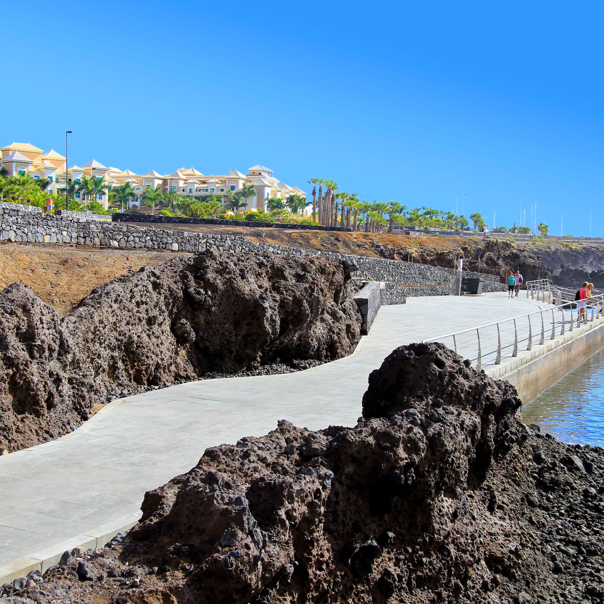 a walkway with rocks and a body of water