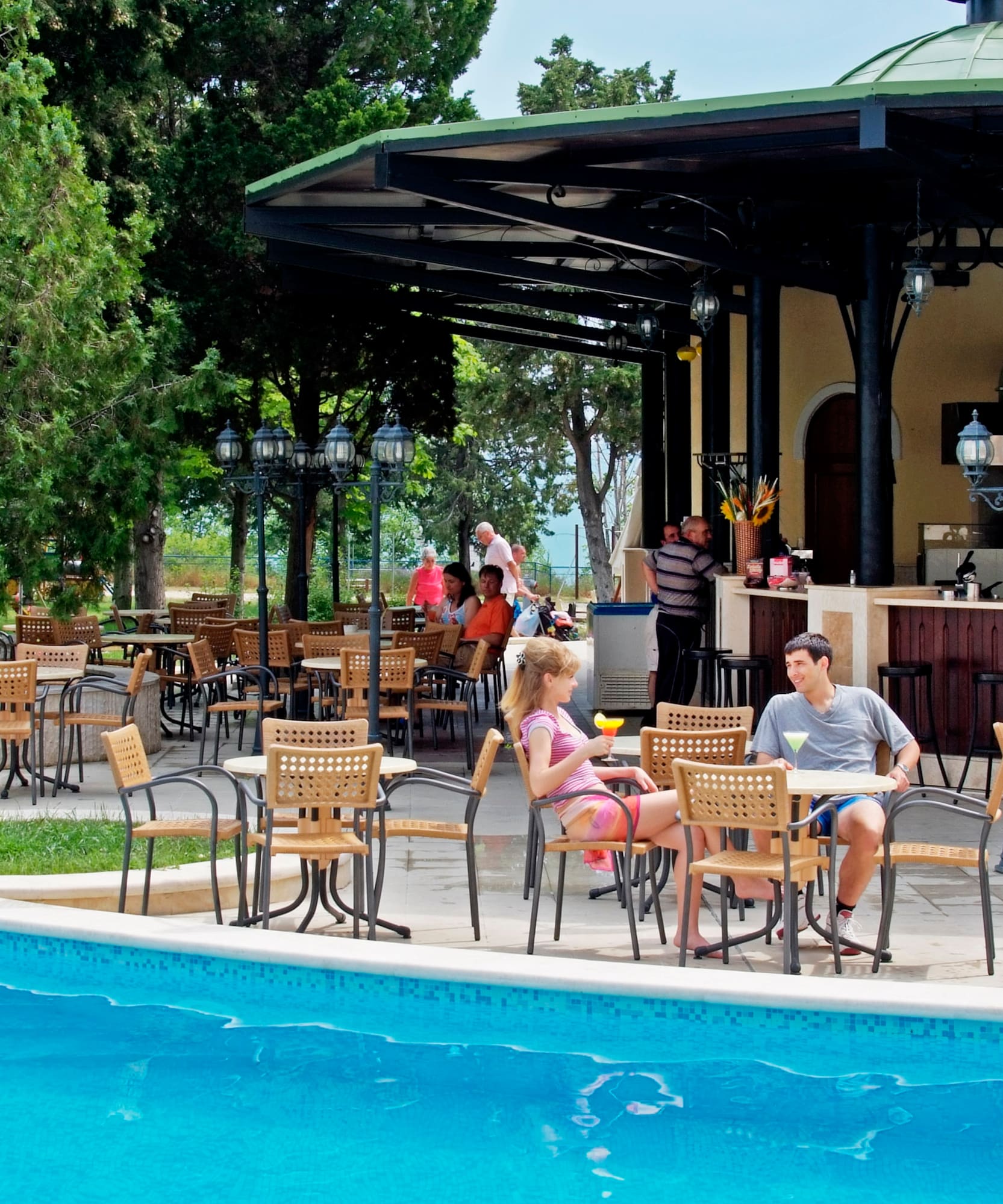 a group of people sitting at tables by a pool