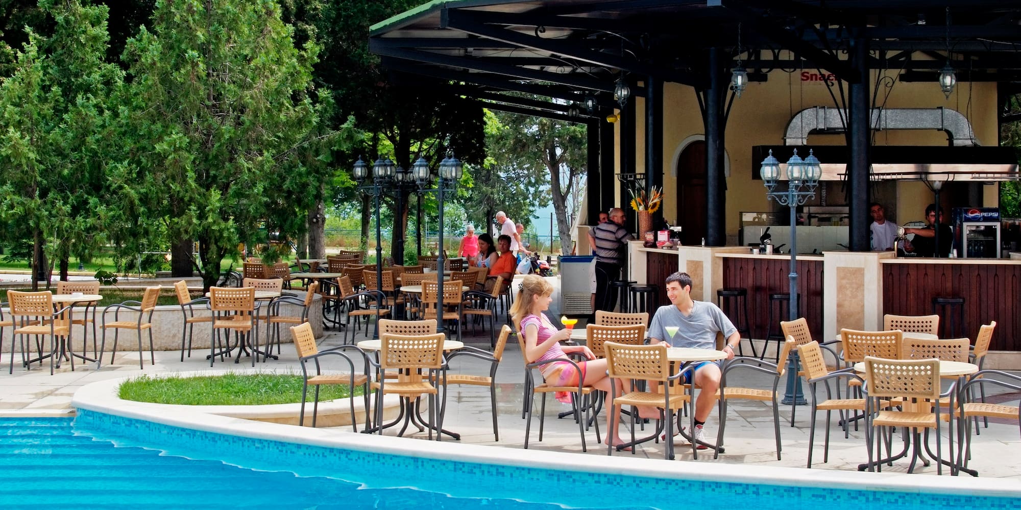 a group of people sitting at tables by a pool