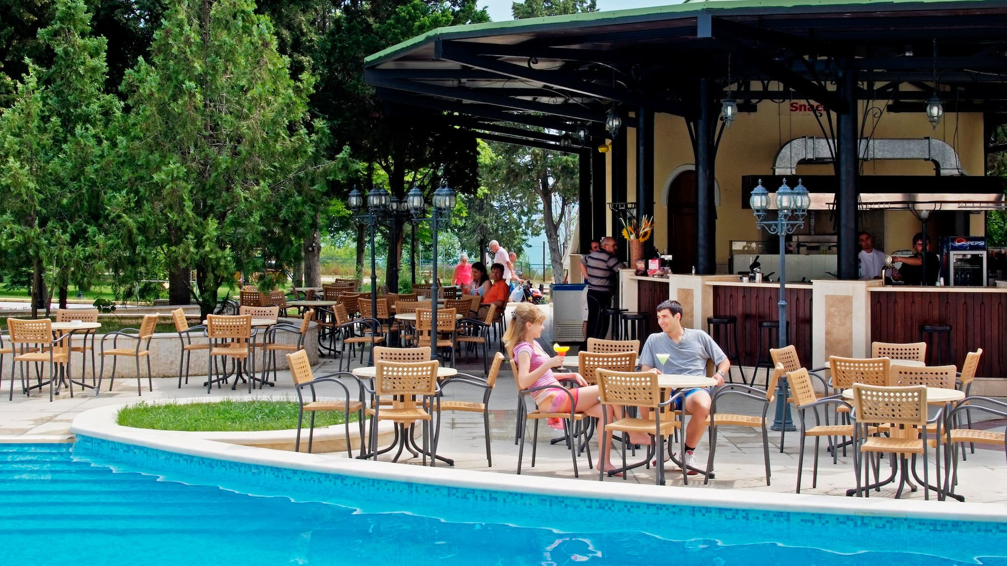 a group of people sitting at tables by a pool