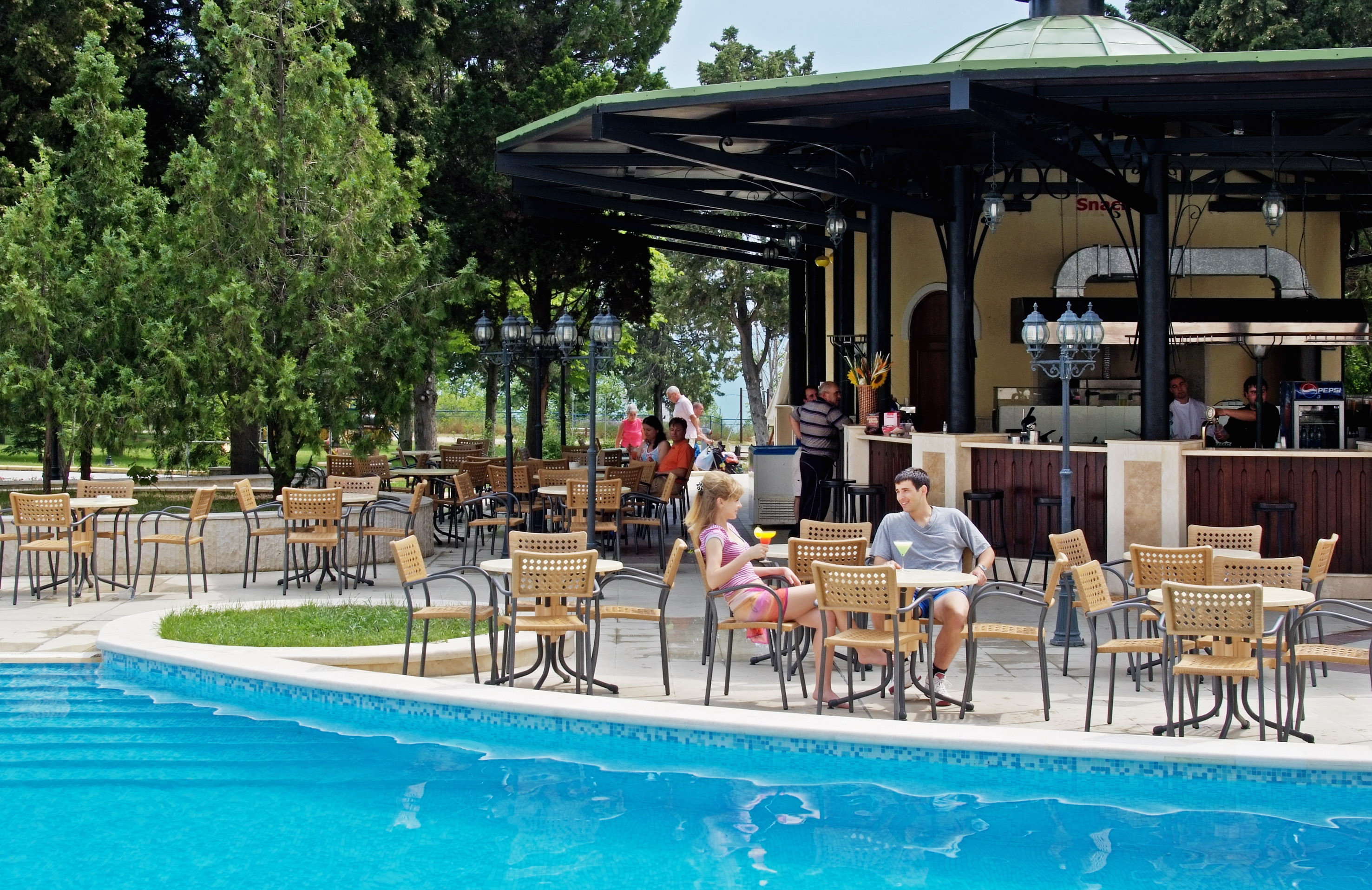 a group of people sitting at tables by a pool