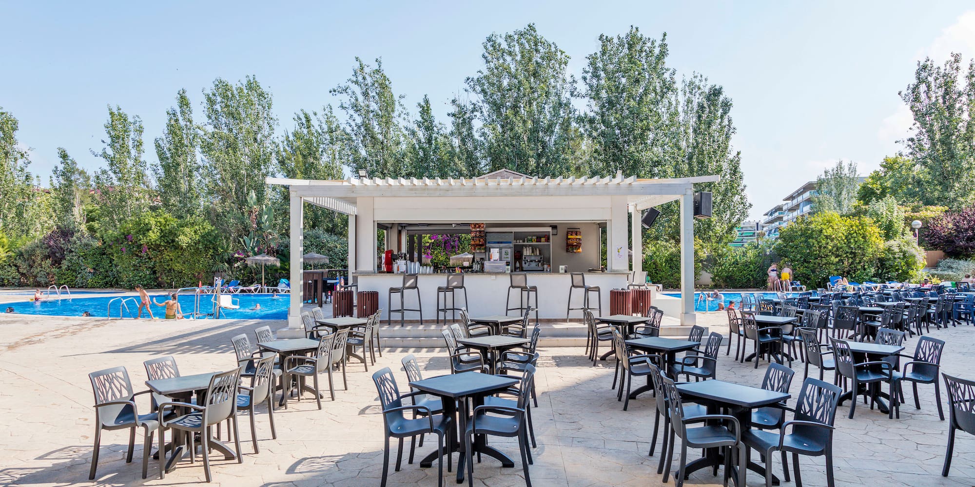a group of tables and chairs outside a pool