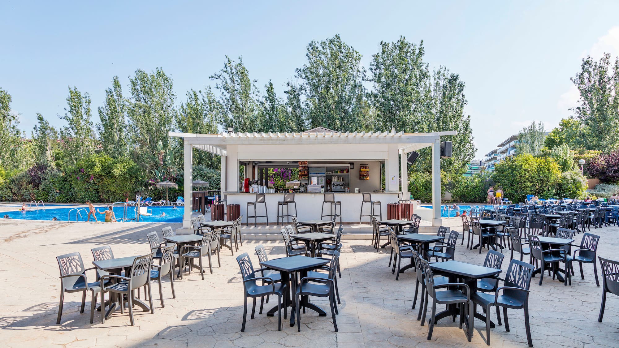 a group of tables and chairs outside a pool