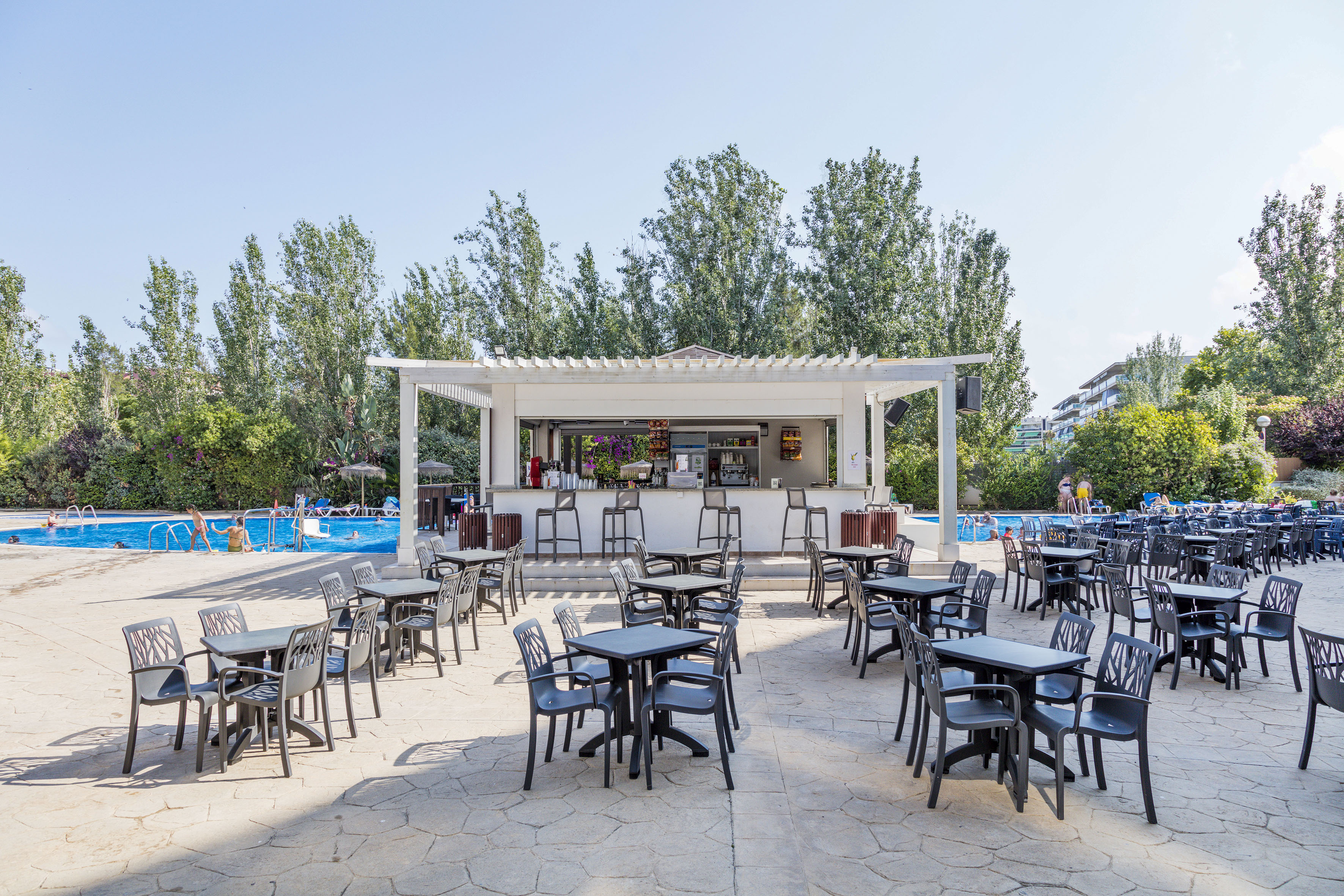 a group of tables and chairs outside a pool