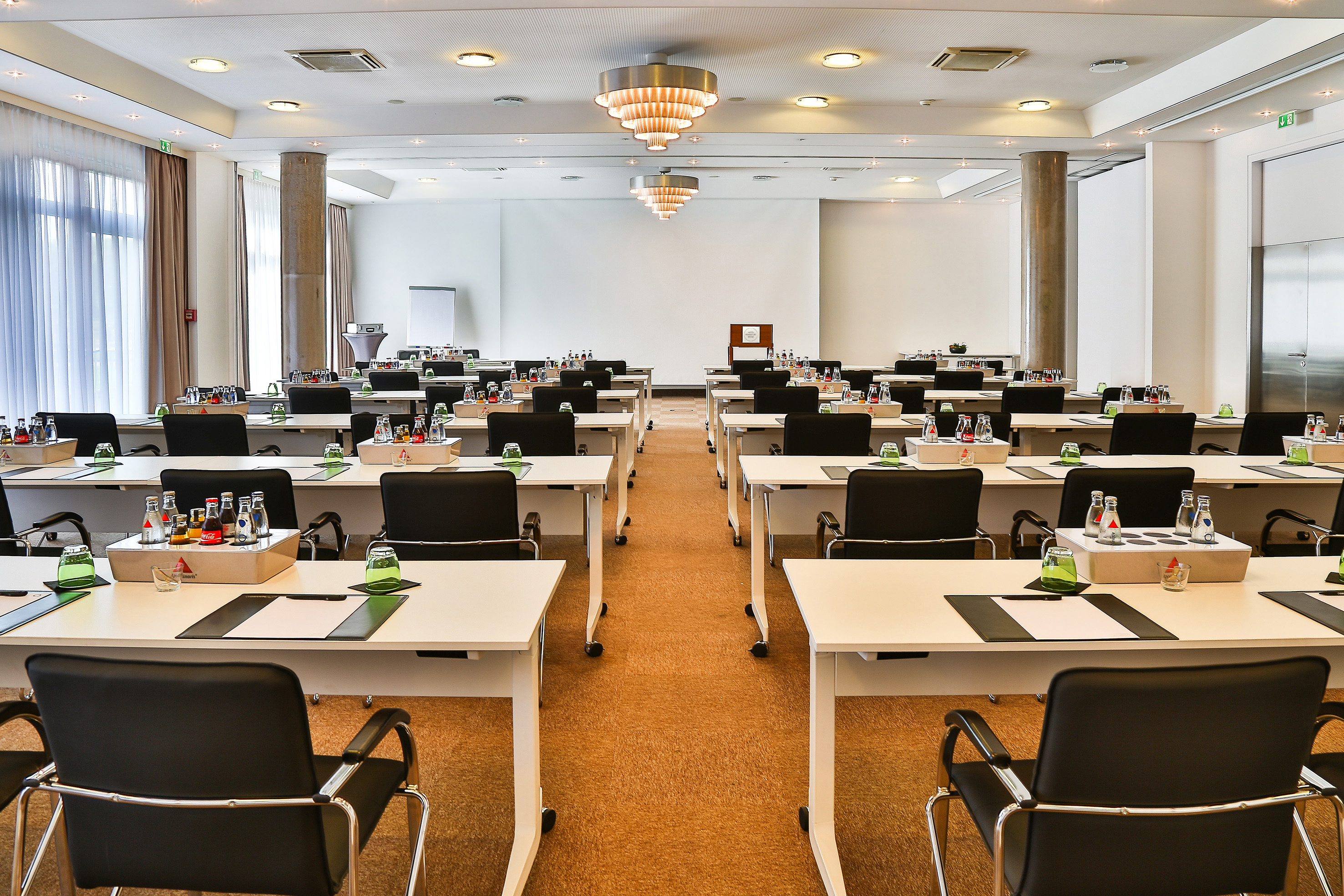 Modern conference room prepared with tables, chairs, and refreshments.