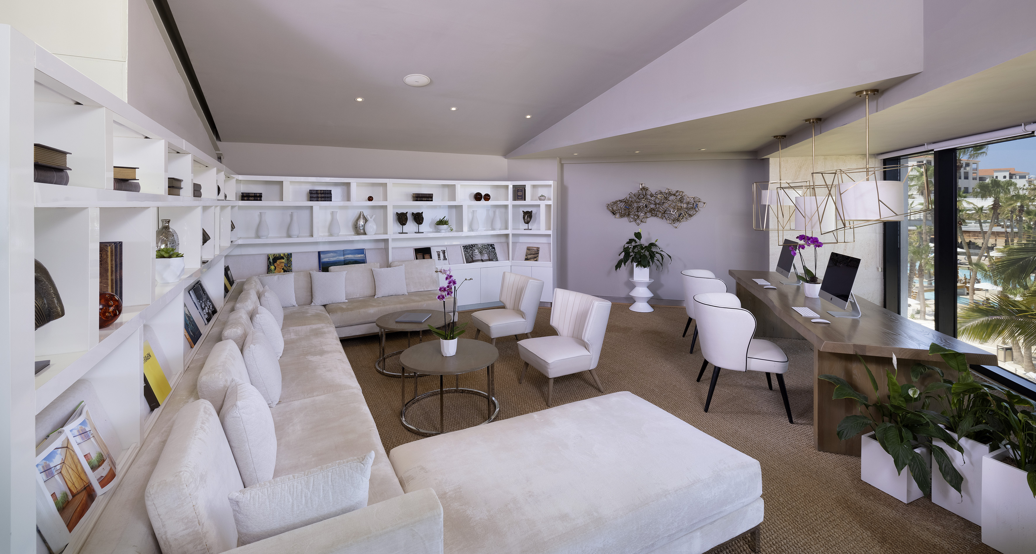 Hotel lobby lounge with white sofa, shelving, and modern work desks.