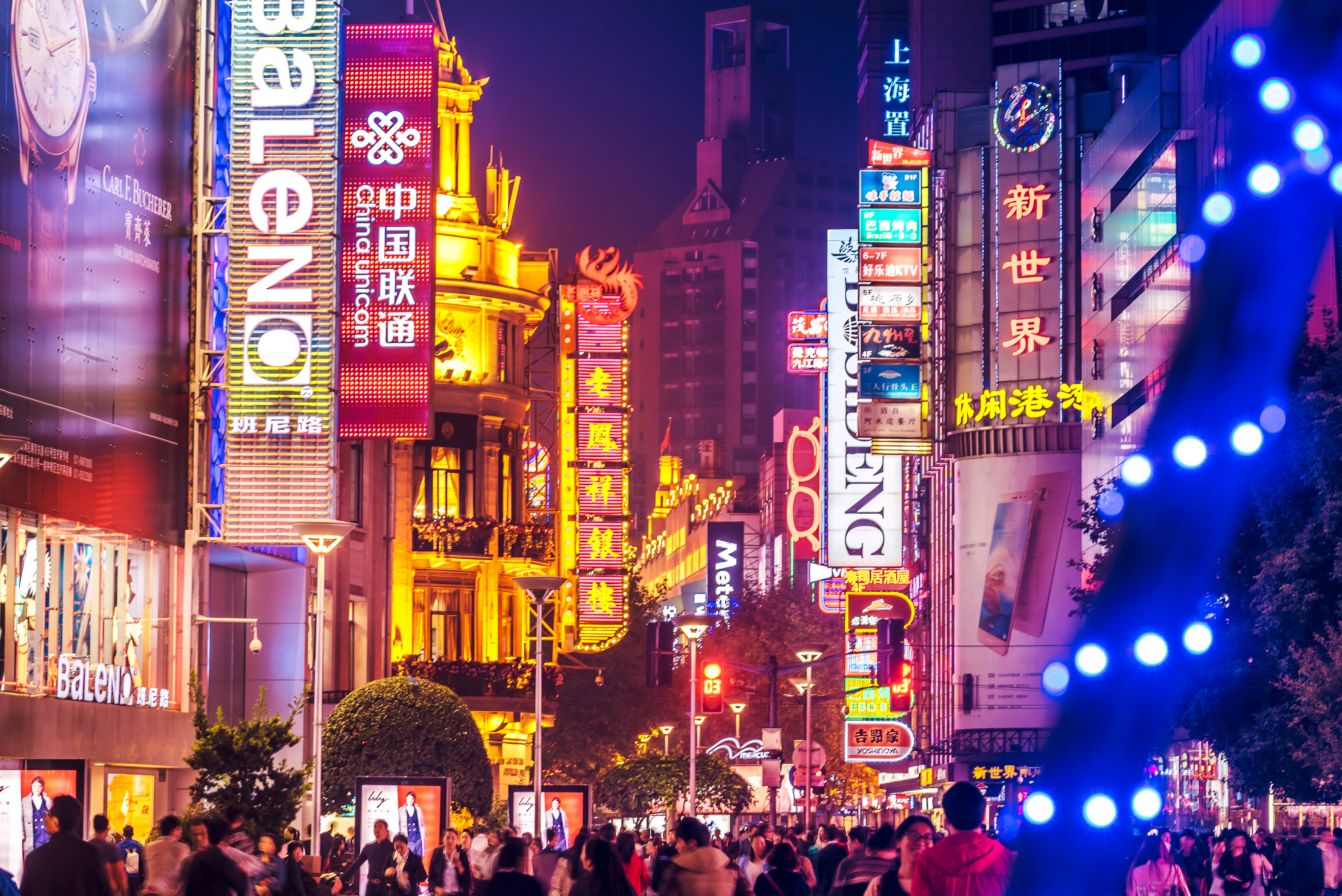 a crowd of people walking on a busy street with neon signs