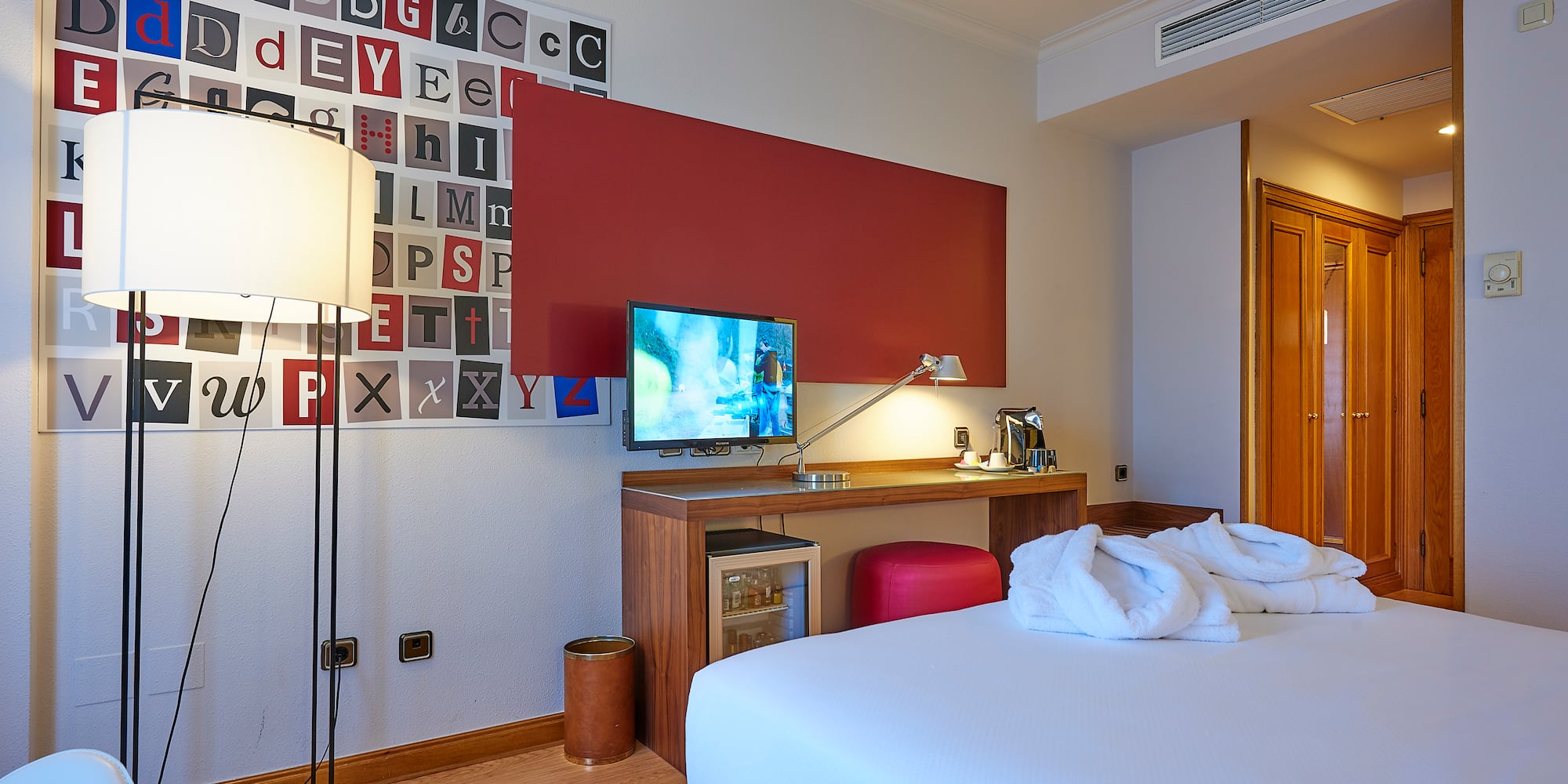 a room with a bed and a desk and a lamp