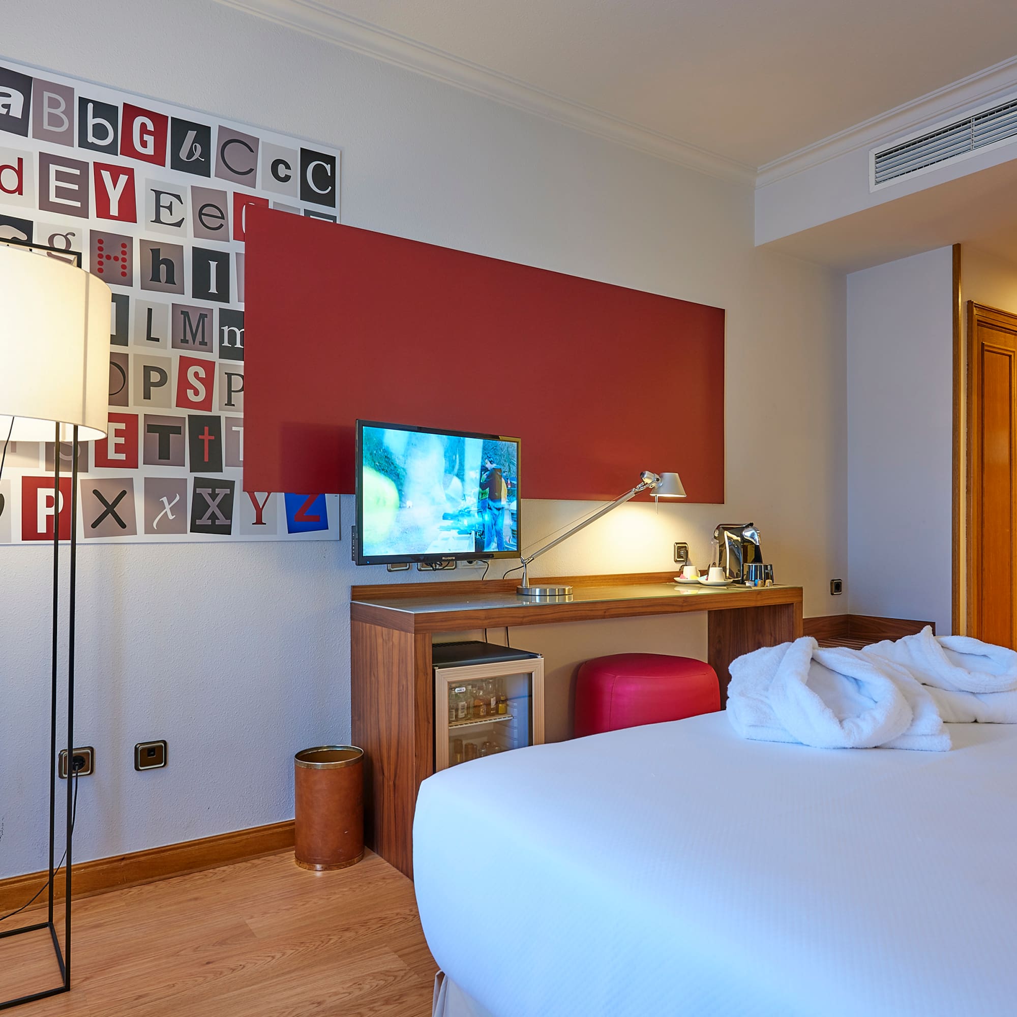 a room with a bed and a desk and a lamp