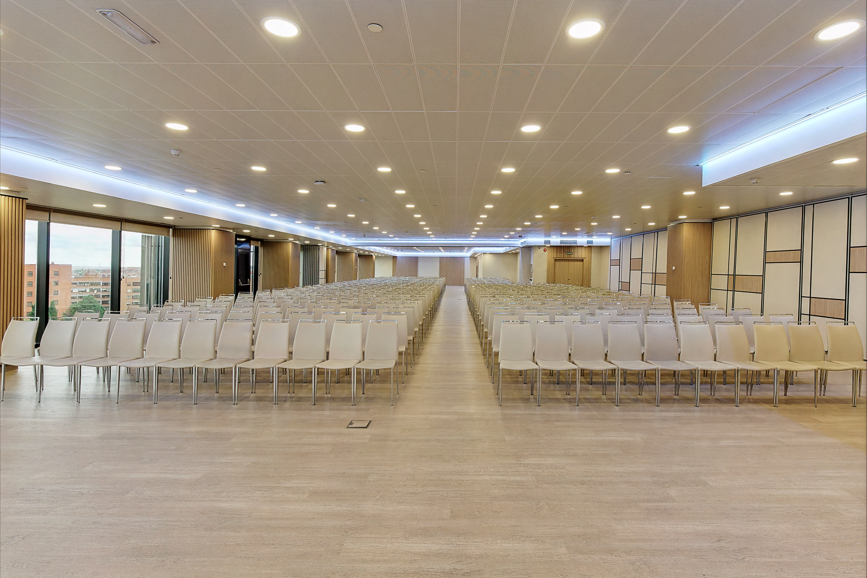 Spacious event hall with theater-style seating, modern design, and city view.