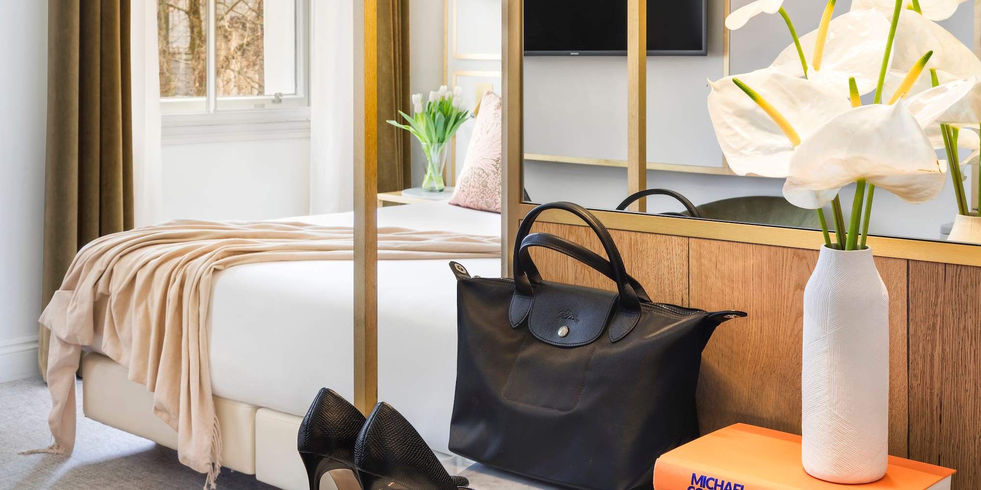a black bag and shoes on a marble surface next to a bed