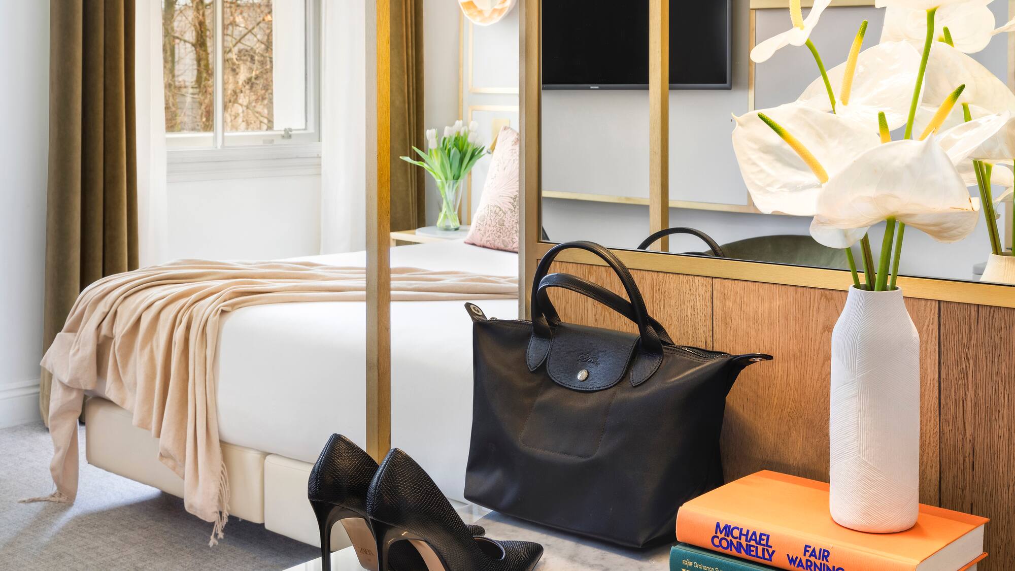 a black bag and shoes on a marble surface next to a bed
