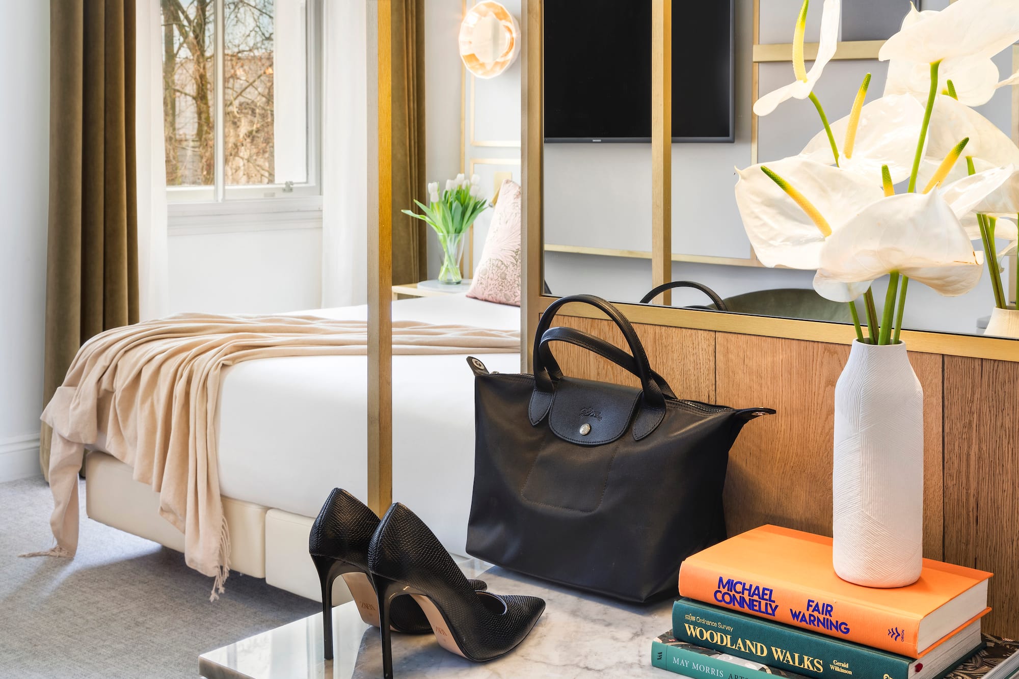 a black bag and shoes on a marble surface next to a bed