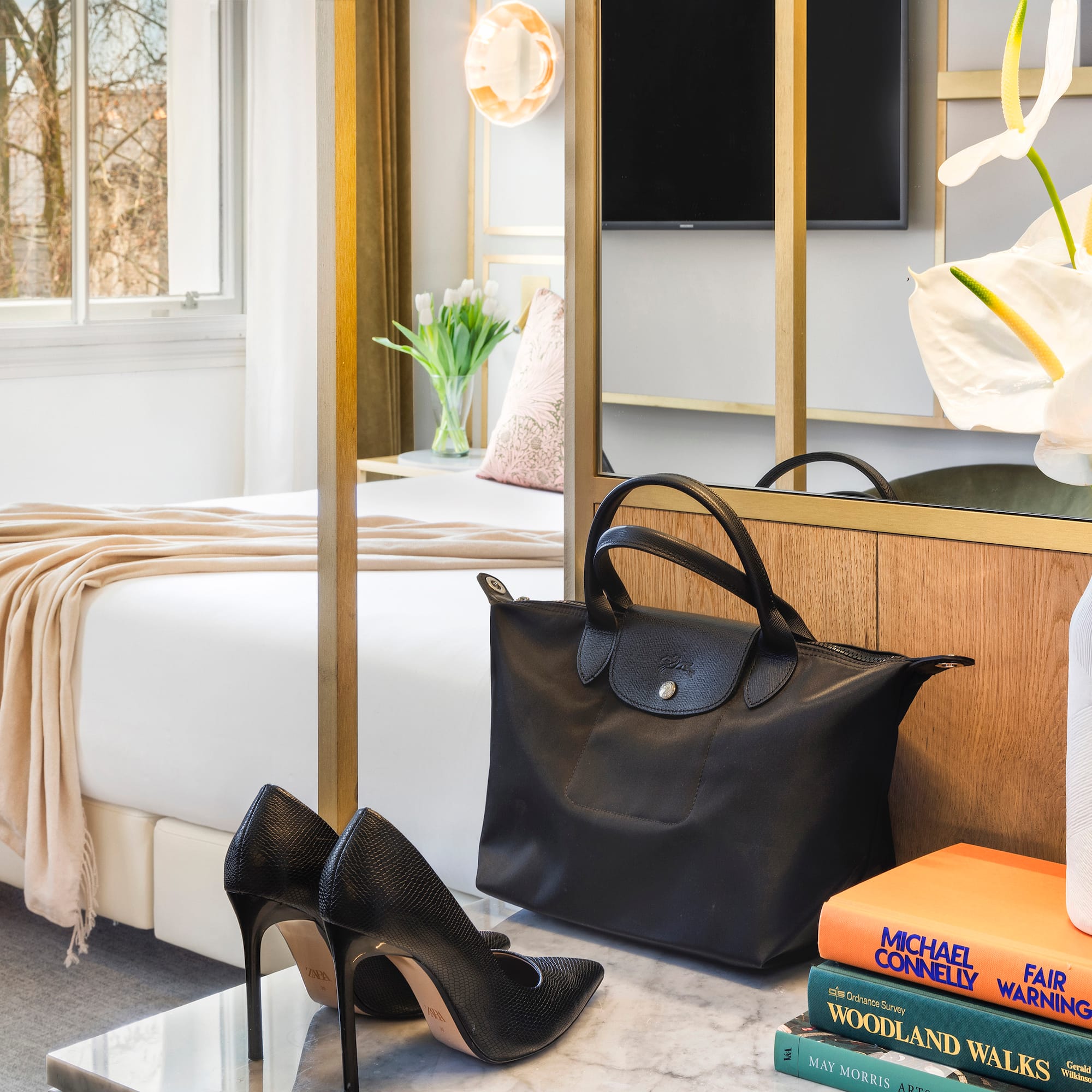 a black bag and shoes on a marble surface next to a bed