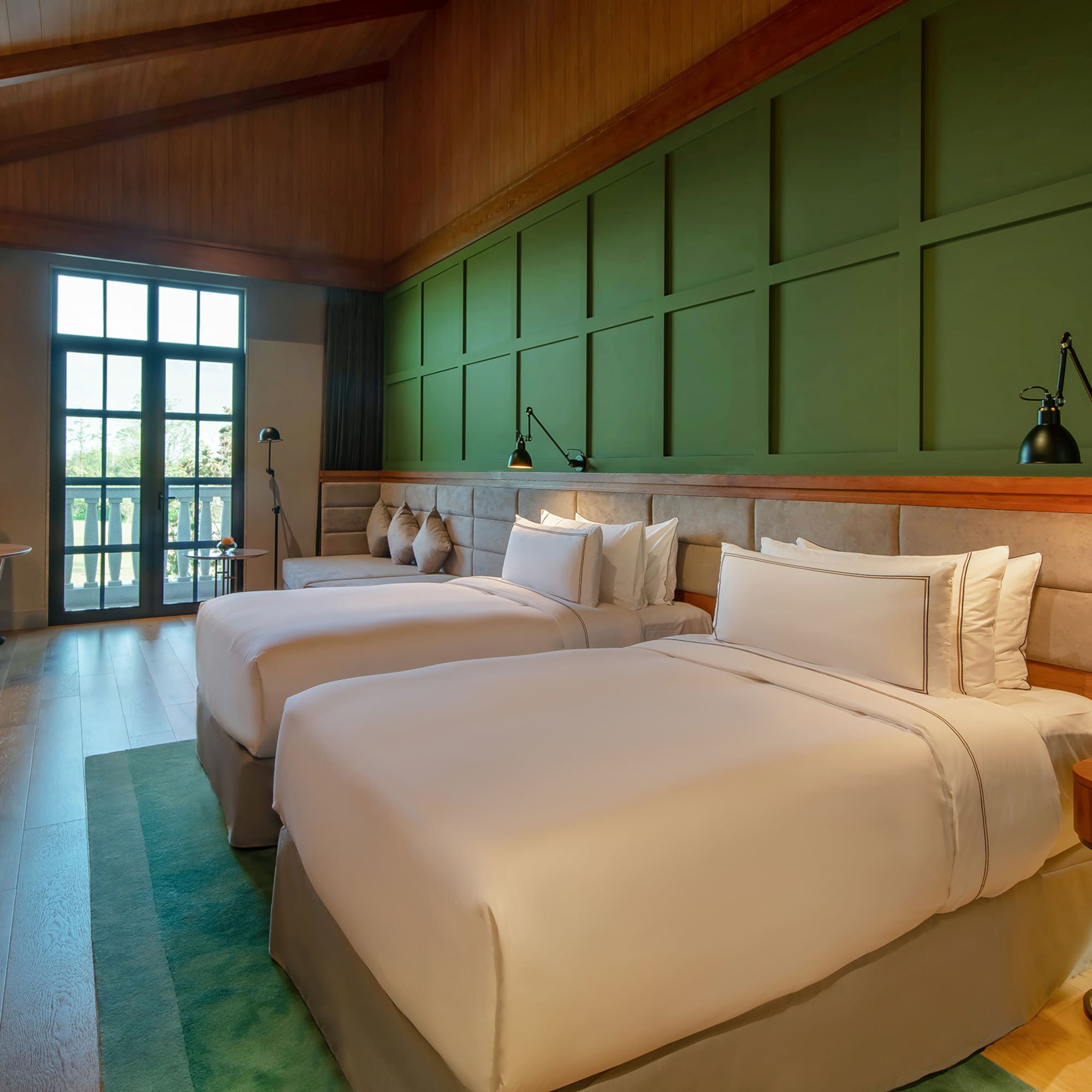 a room with two beds and a green wall