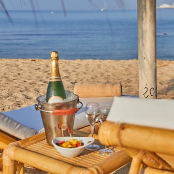 a champagne bottle and wine glasses on a table on a beach