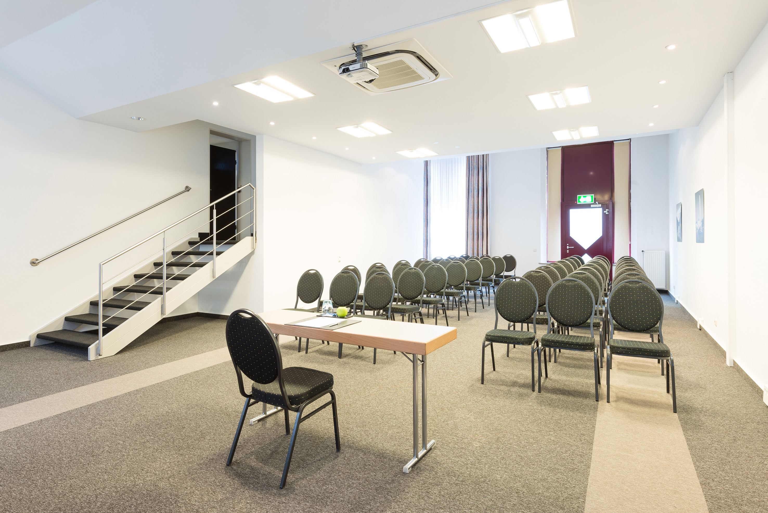 Empty modern conference room with chairs, projector, table, and staircase.