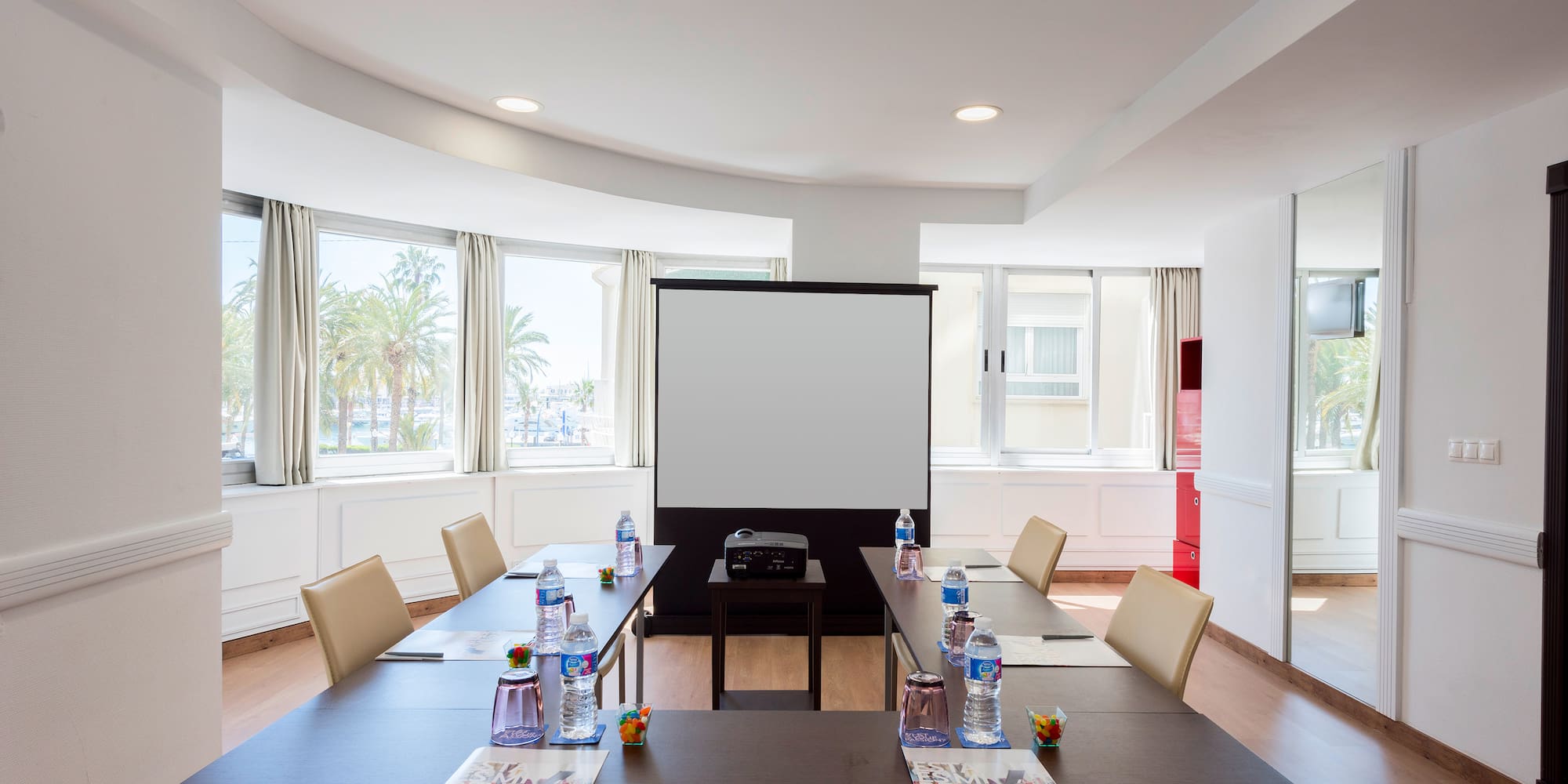 a room with a projector screen and tables