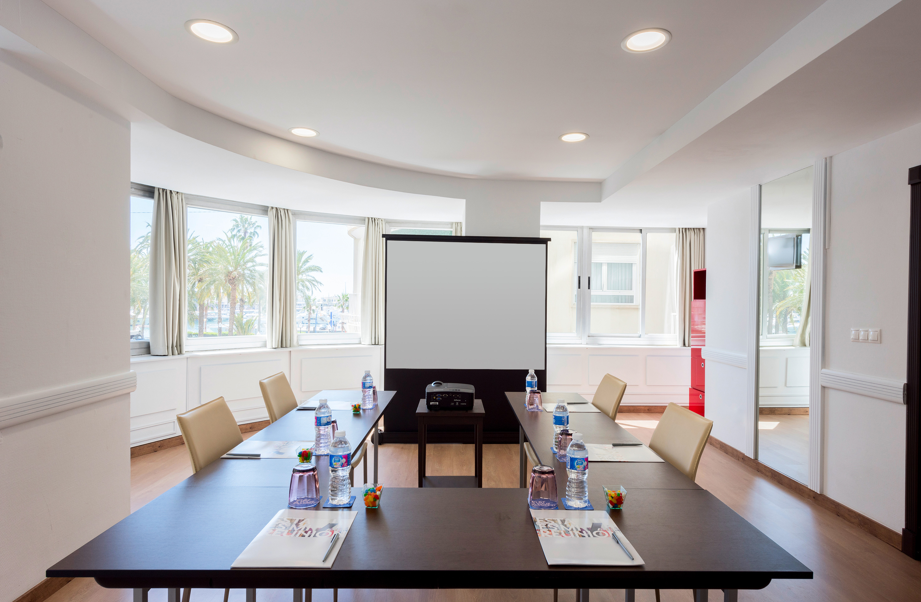 a room with a projector screen and tables