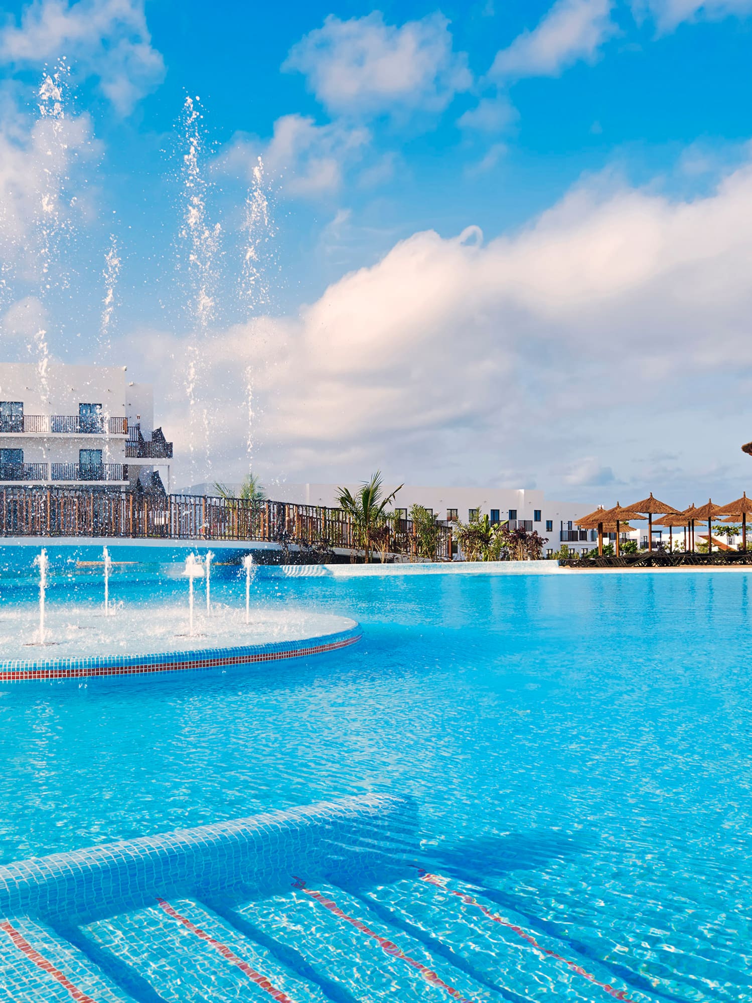 a pool with water fountains and a building