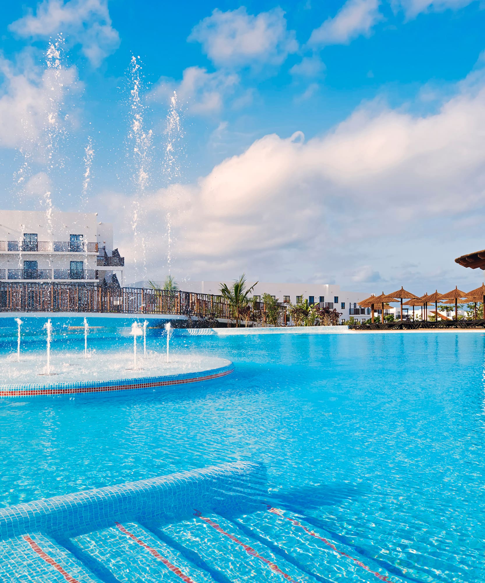 a pool with water fountains and a building
