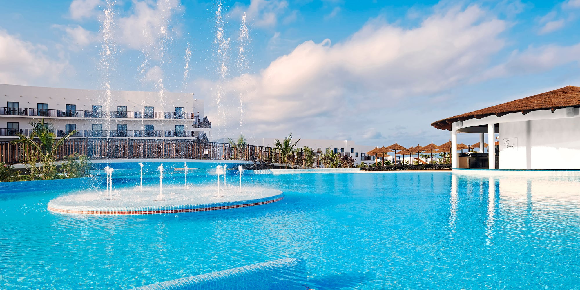 a pool with water fountains and a building