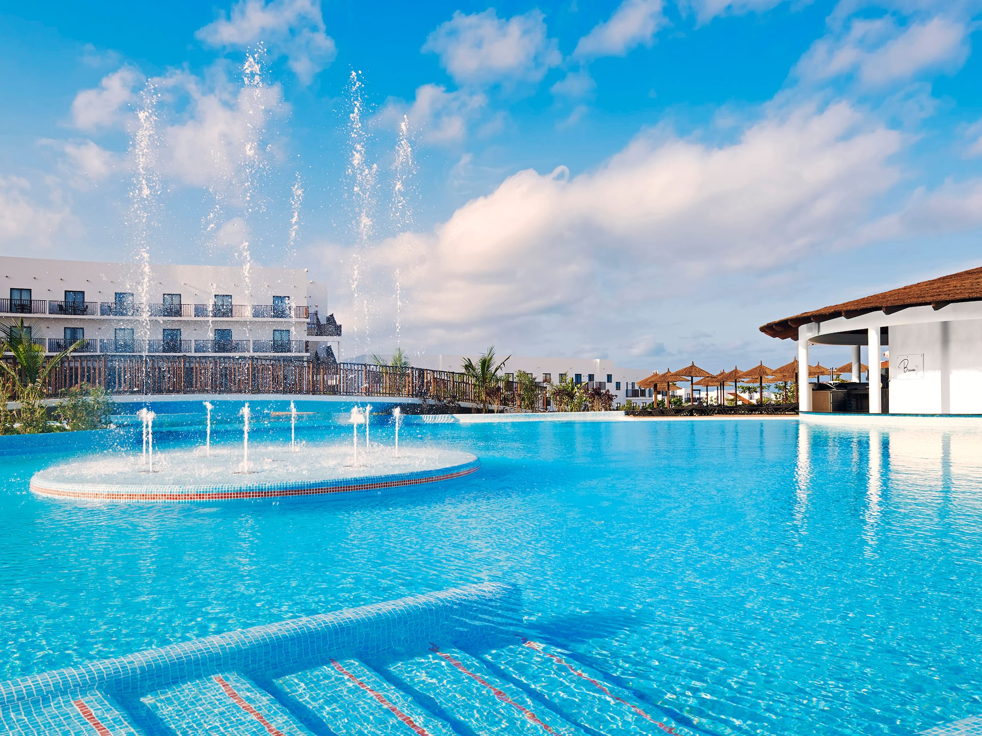 a pool with water fountains and a building