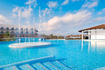 a pool with water fountains and a building