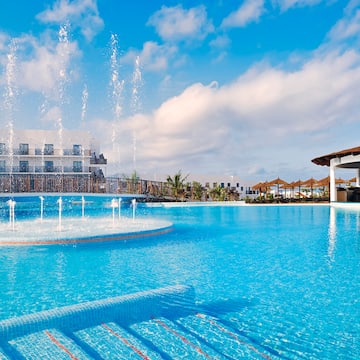 a pool with water fountains and a building