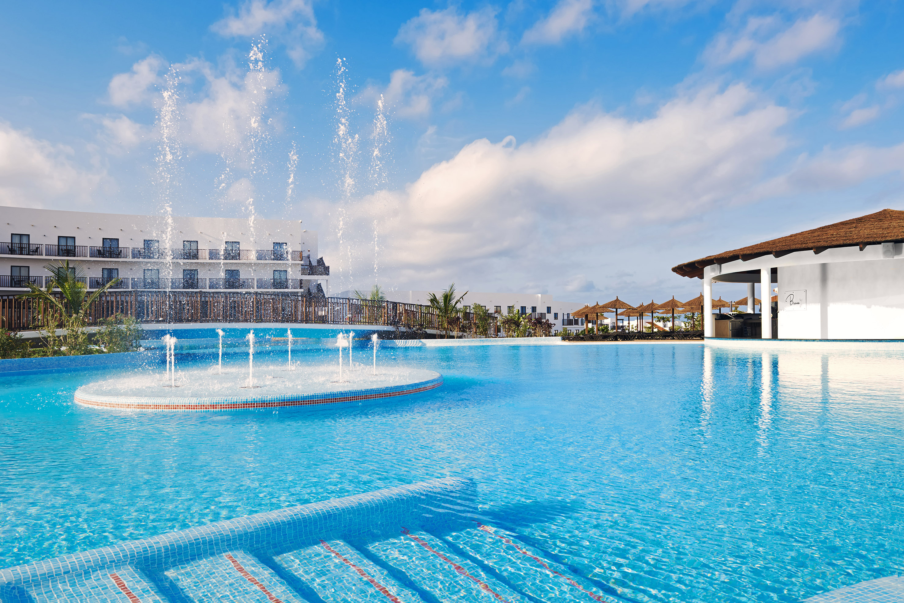 a pool with water fountains and a building