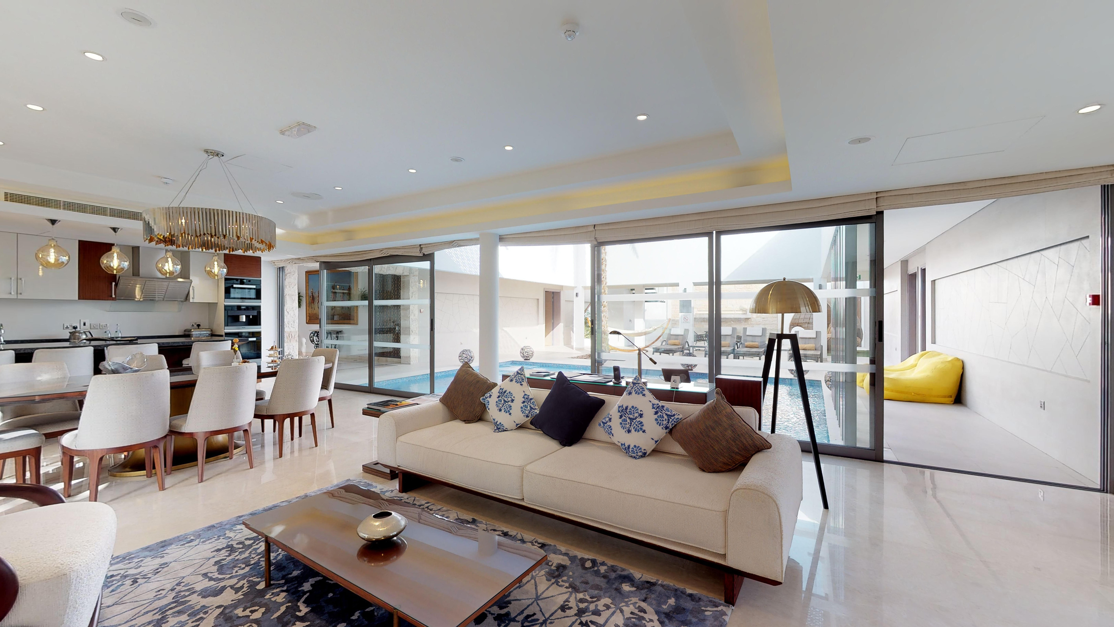 Modern open-concept living room, dining, and kitchen with pool view.