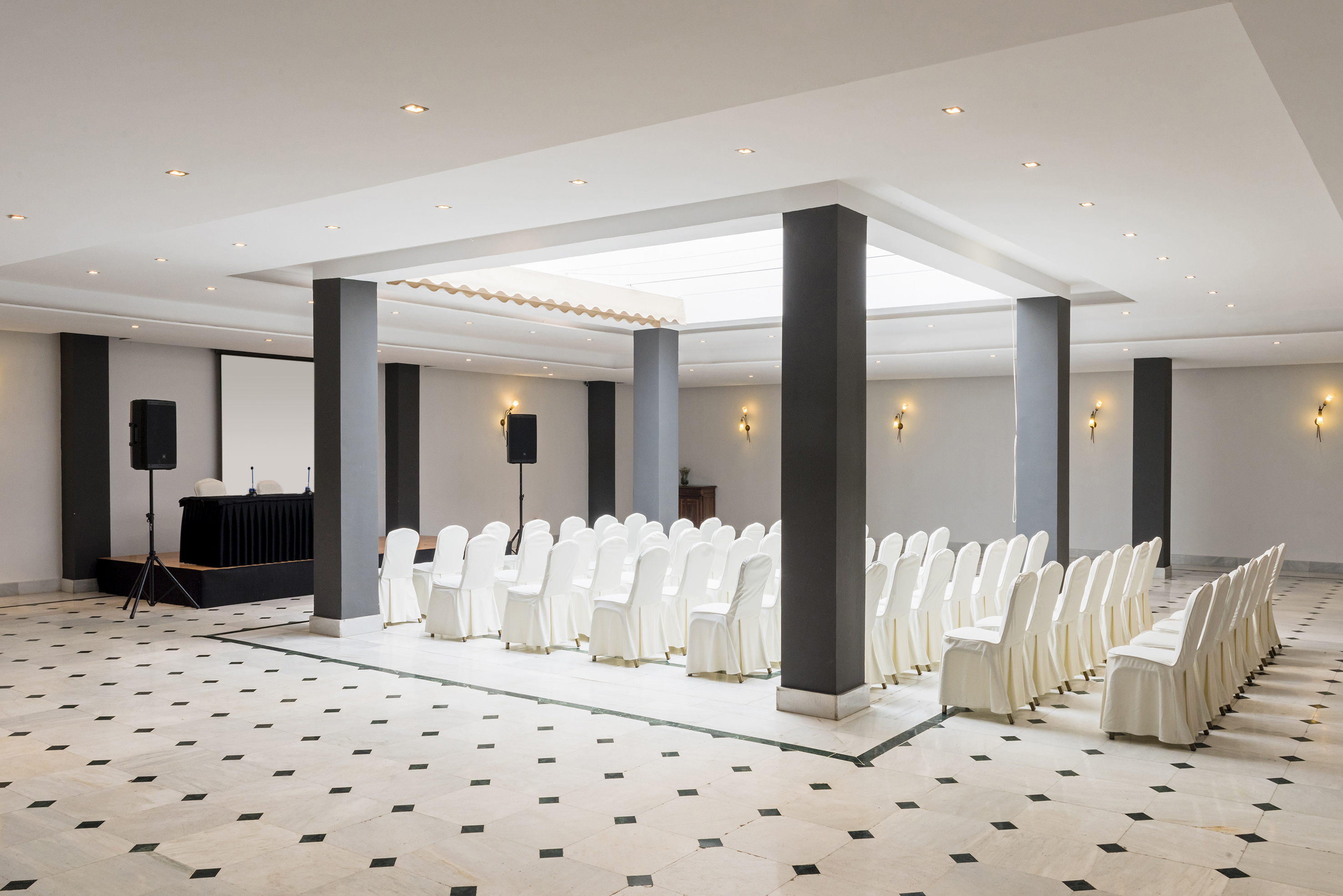 a room with white chairs and black columns