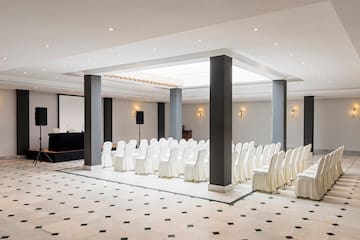 a room with white chairs and black columns