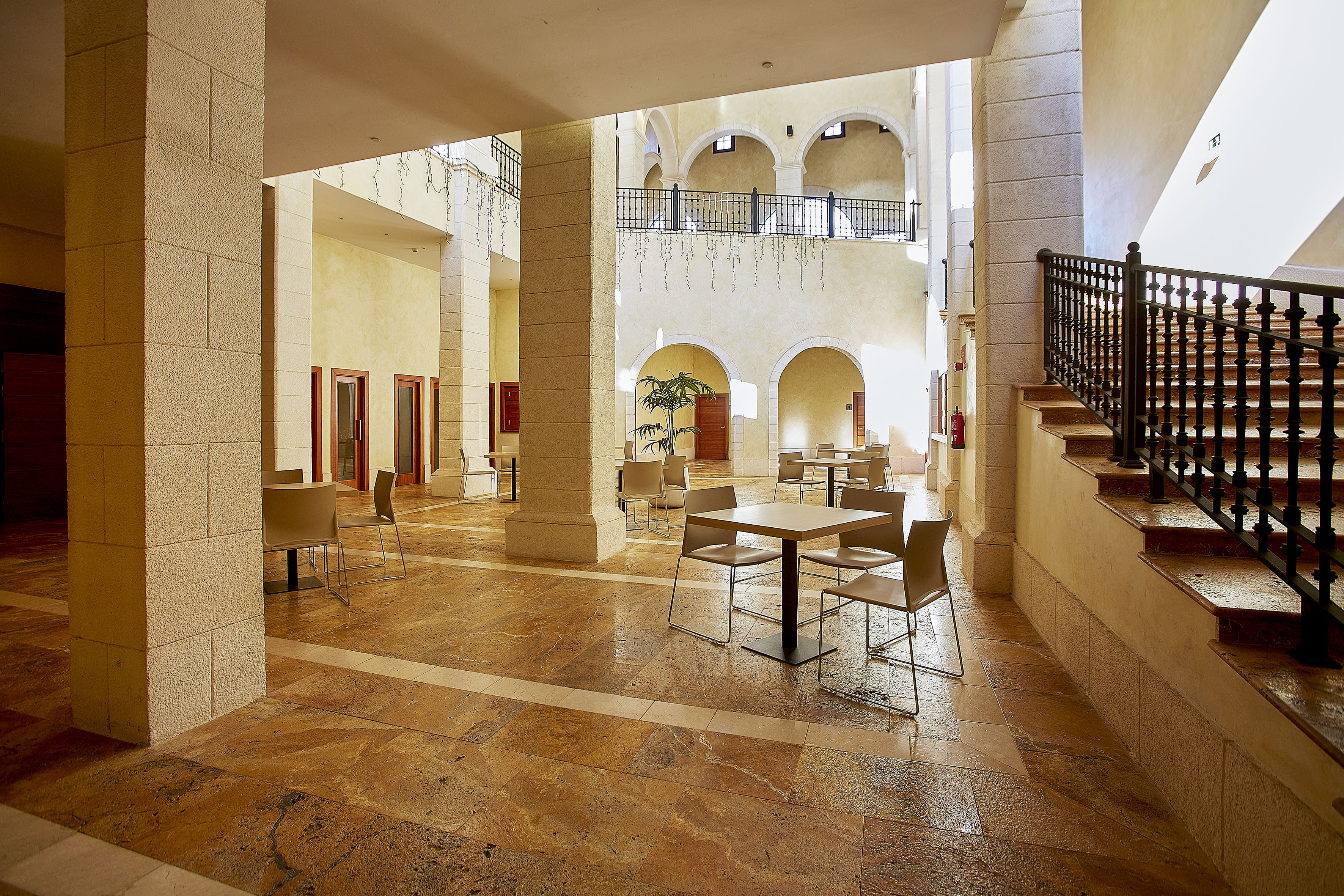 Hotel atrium with stone arches, columns, tiled floor, and modern cafe seating. - Foyer Benidorm - The Level at Meliá Villaitana, Benidorm