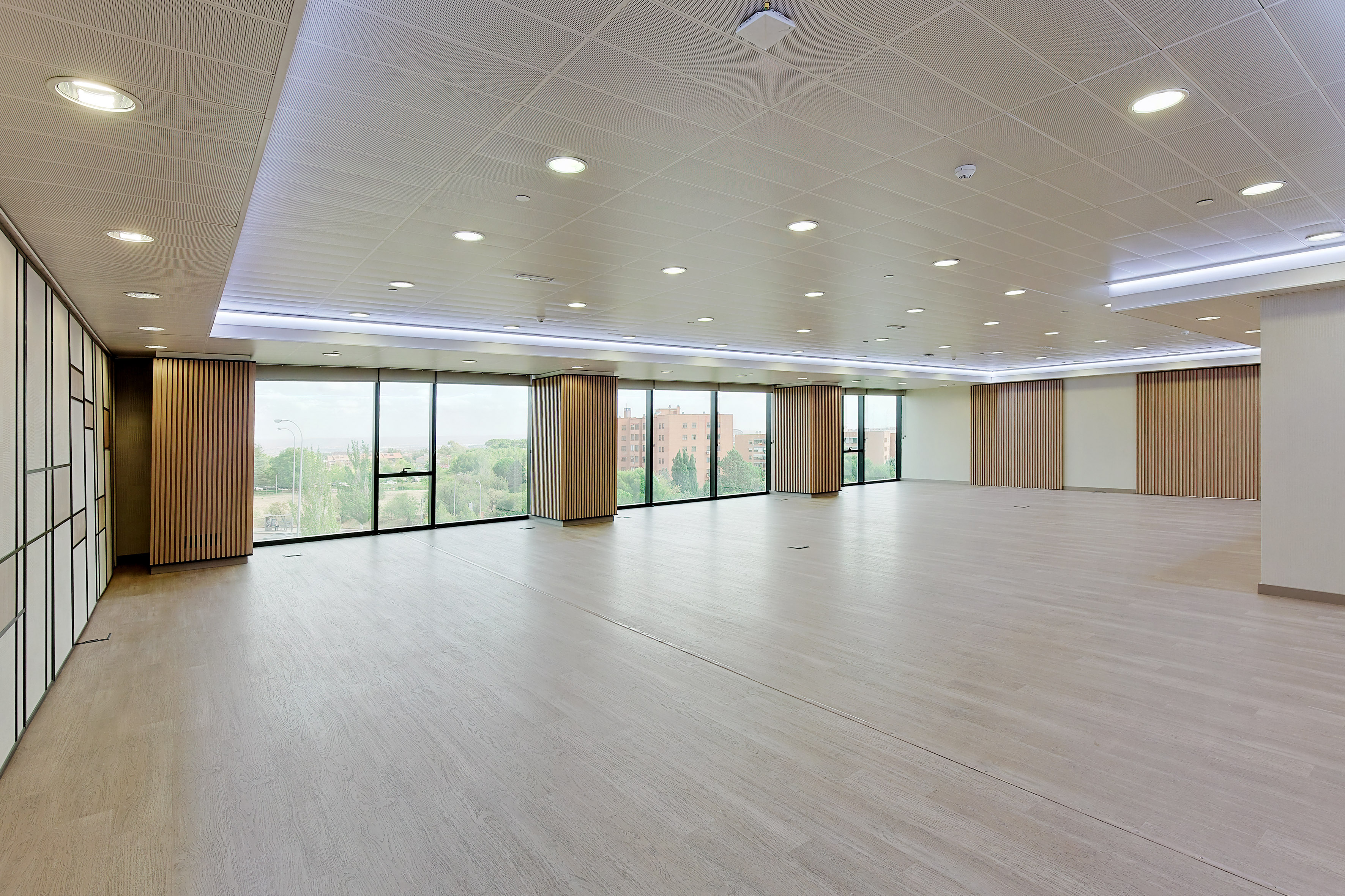 Spacious modern event room with large windows, wood floor, and natural light.