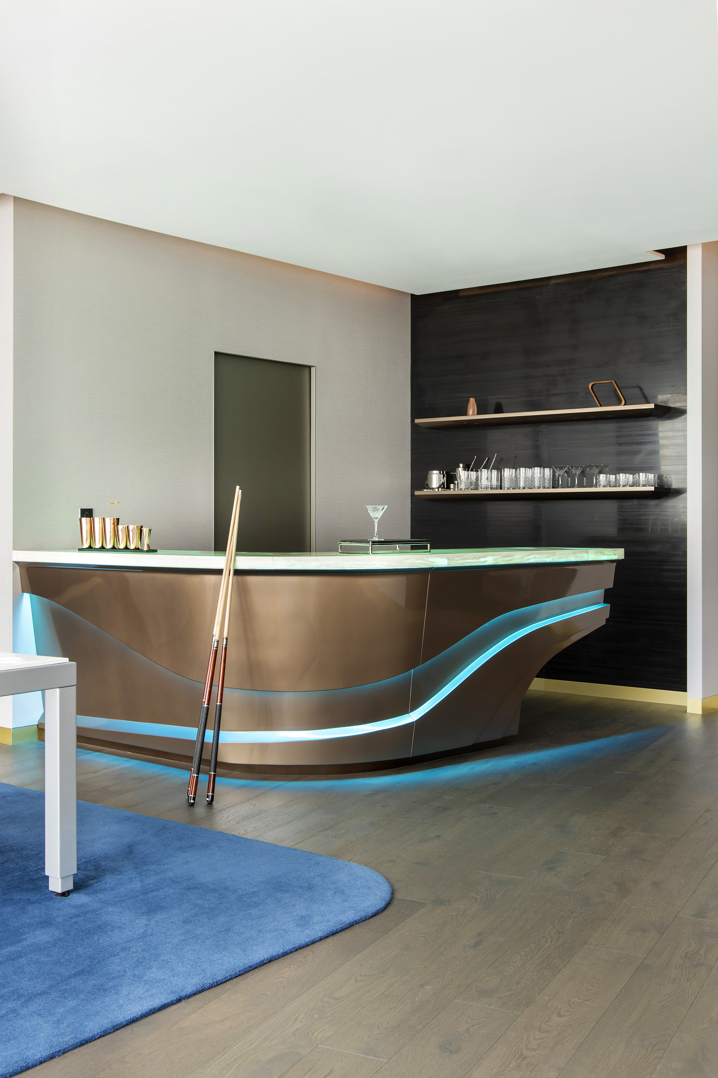 Modern home bar with blue LED lighting, cocktail setup, and pool cues.