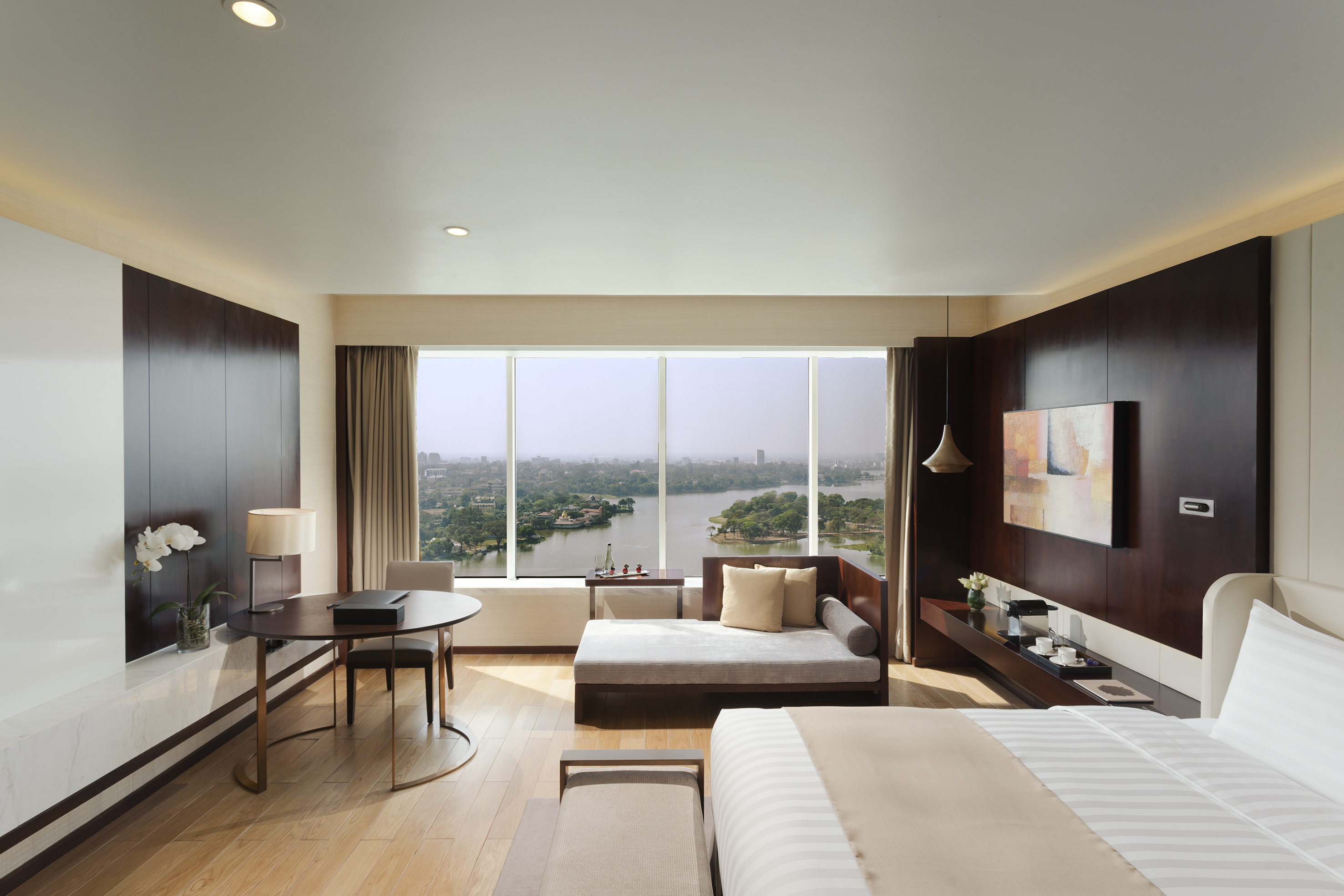 Luxury hotel room with lake view, king bed, chaise lounge, and desk.