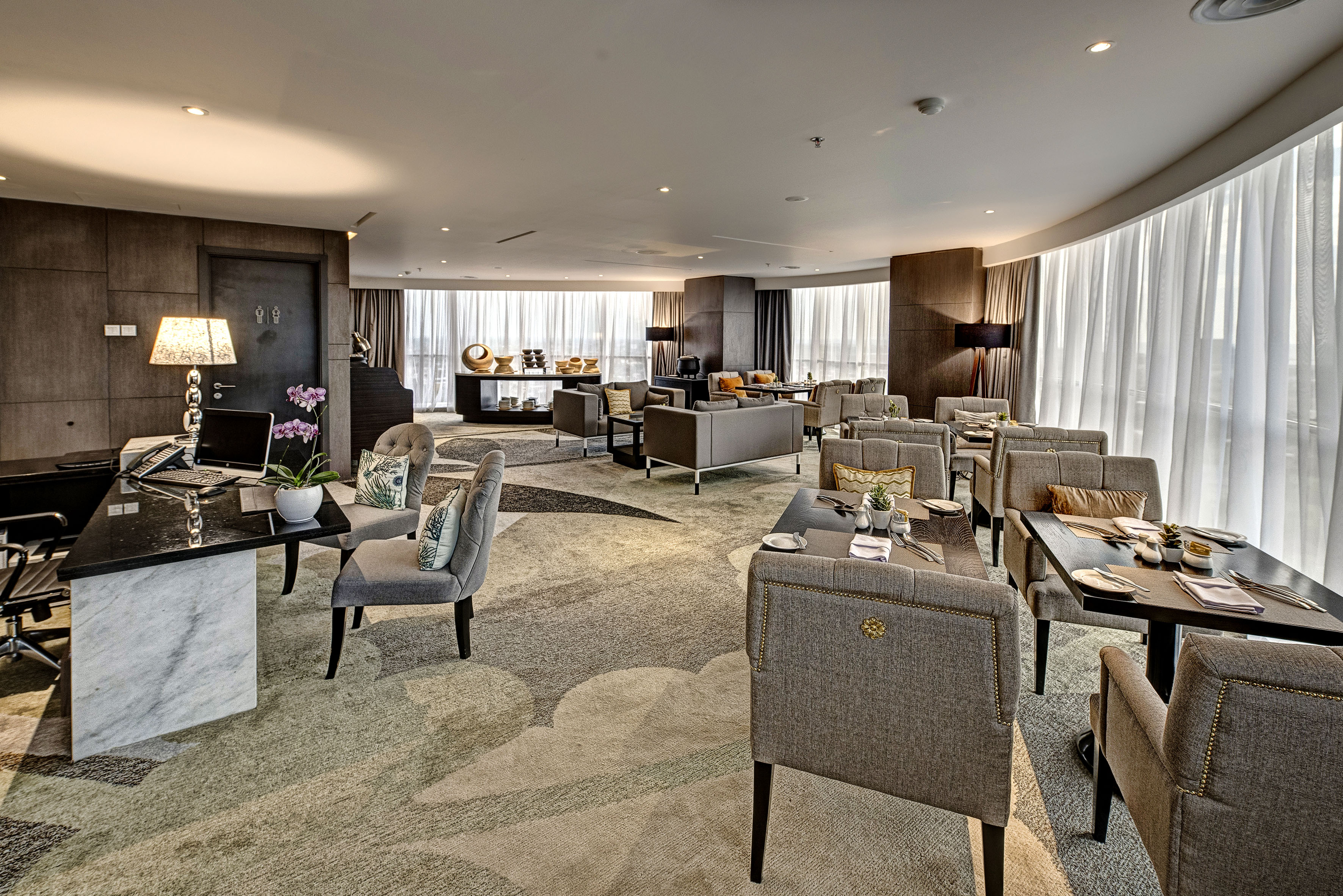 Modern luxury hotel lounge with dining, sofa seating, and reception desk.