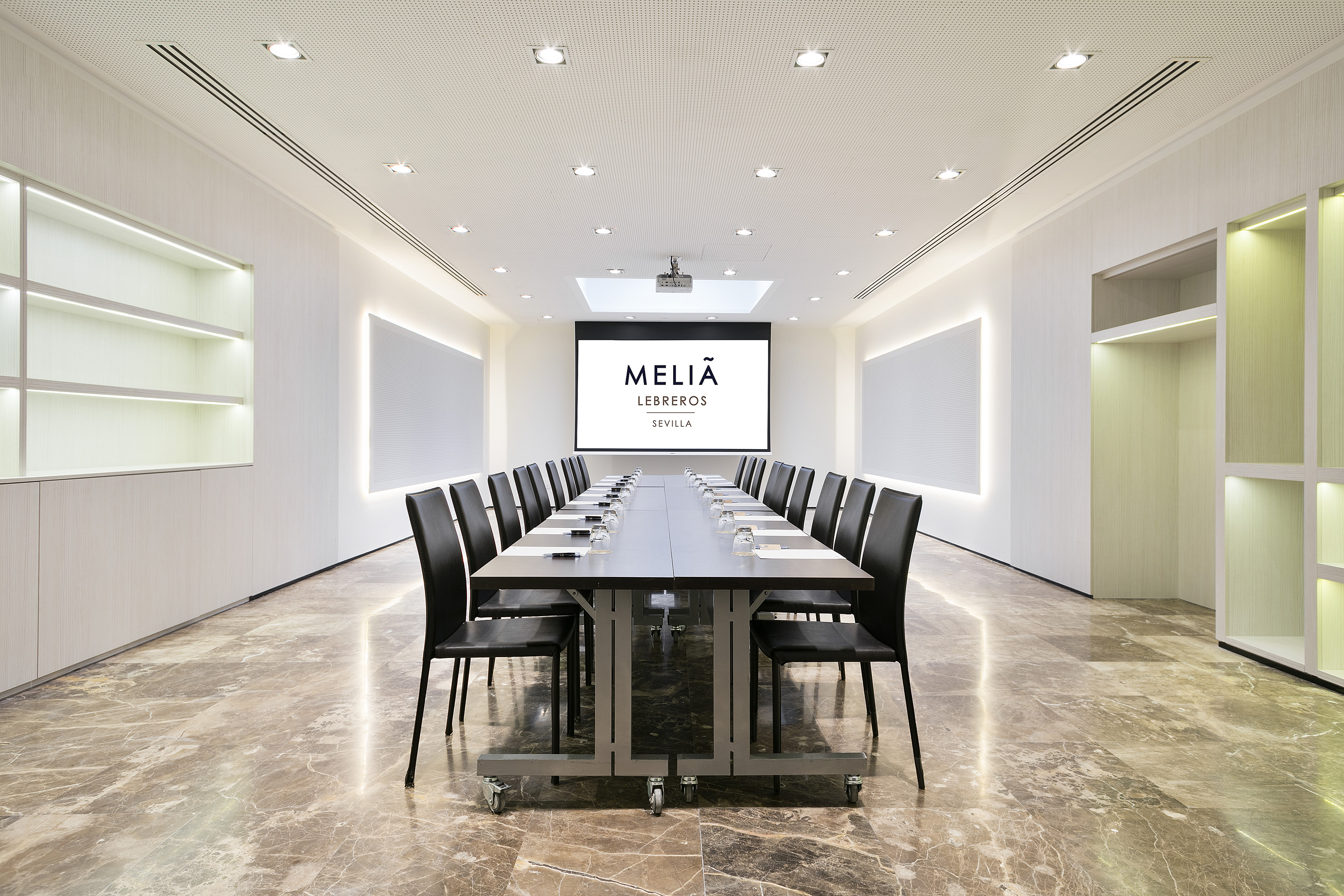 Meliá Lebreros Sevilla meeting room with long table, chairs, and screen.