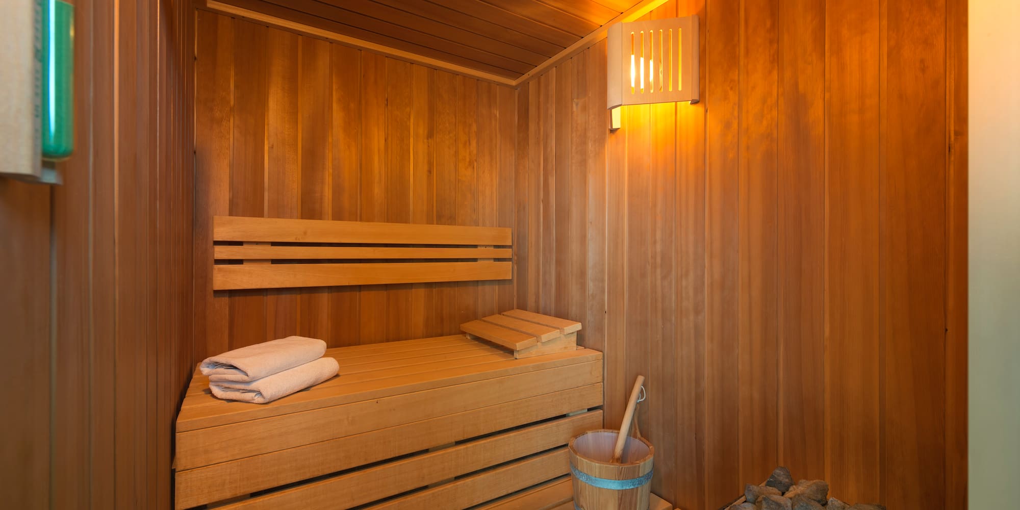 a wooden sauna with a bucket and a towel