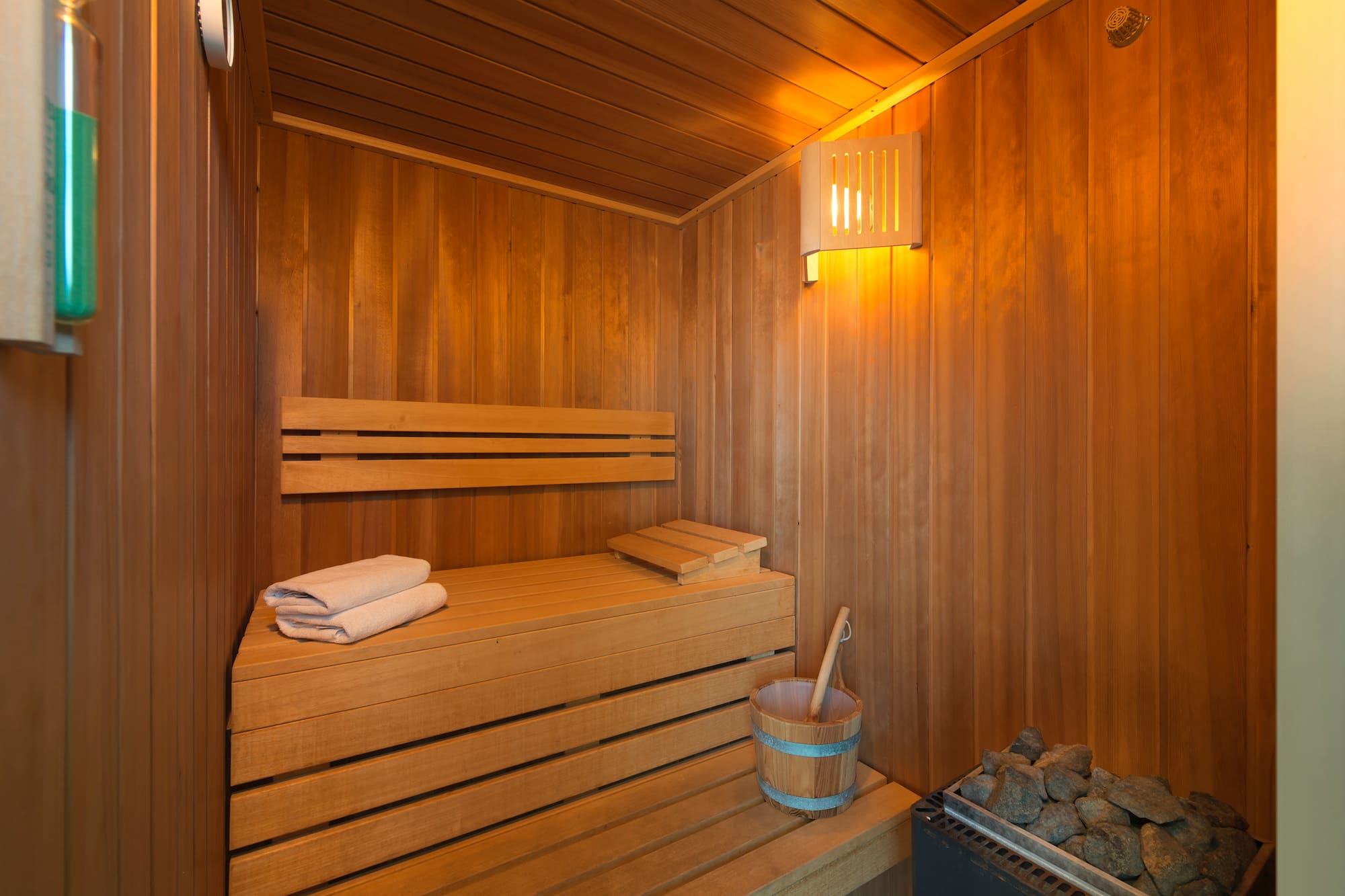 a wooden sauna with a bucket and a towel